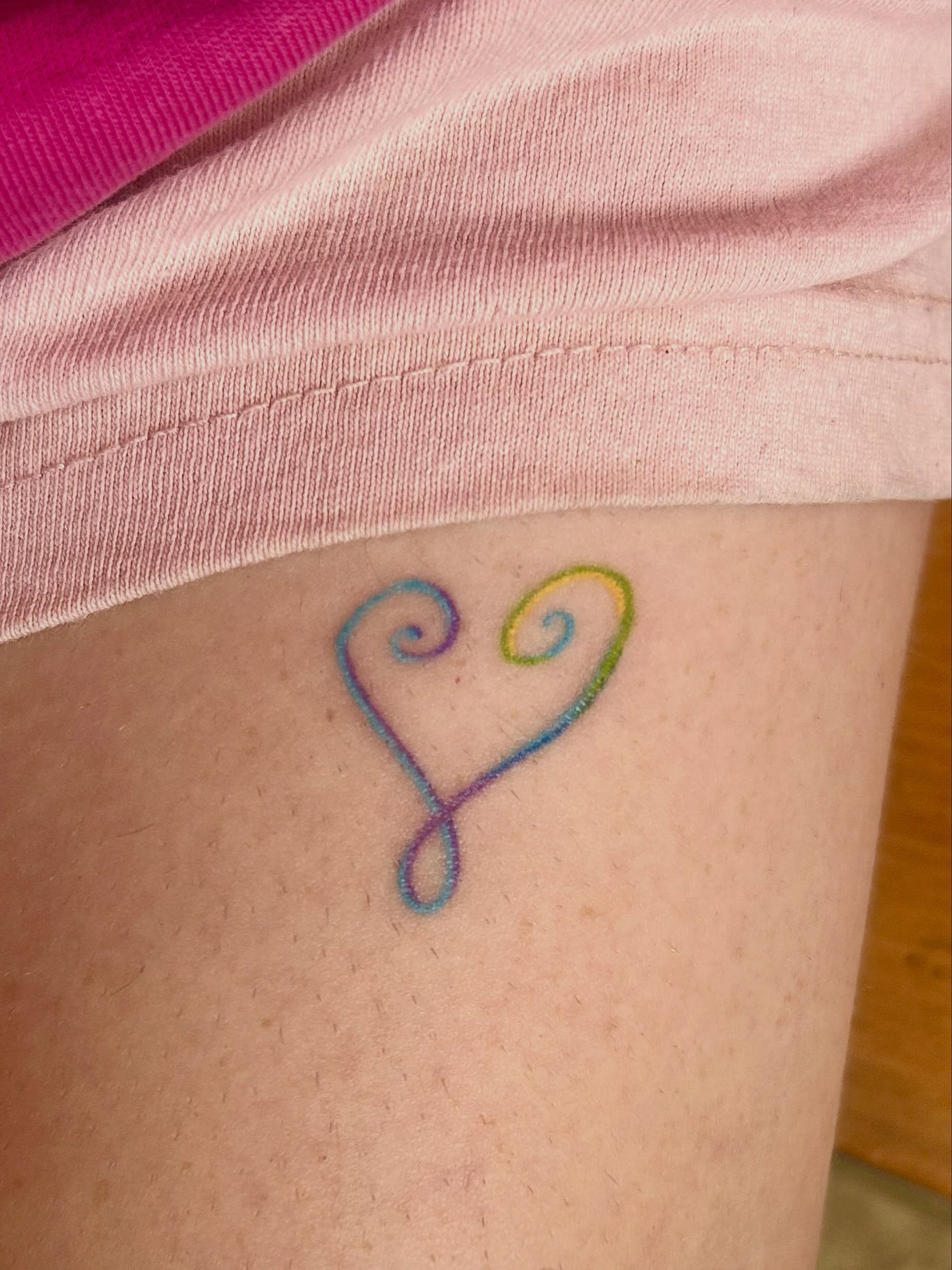 Heart fine line tattoo on the thigh by Nicolette