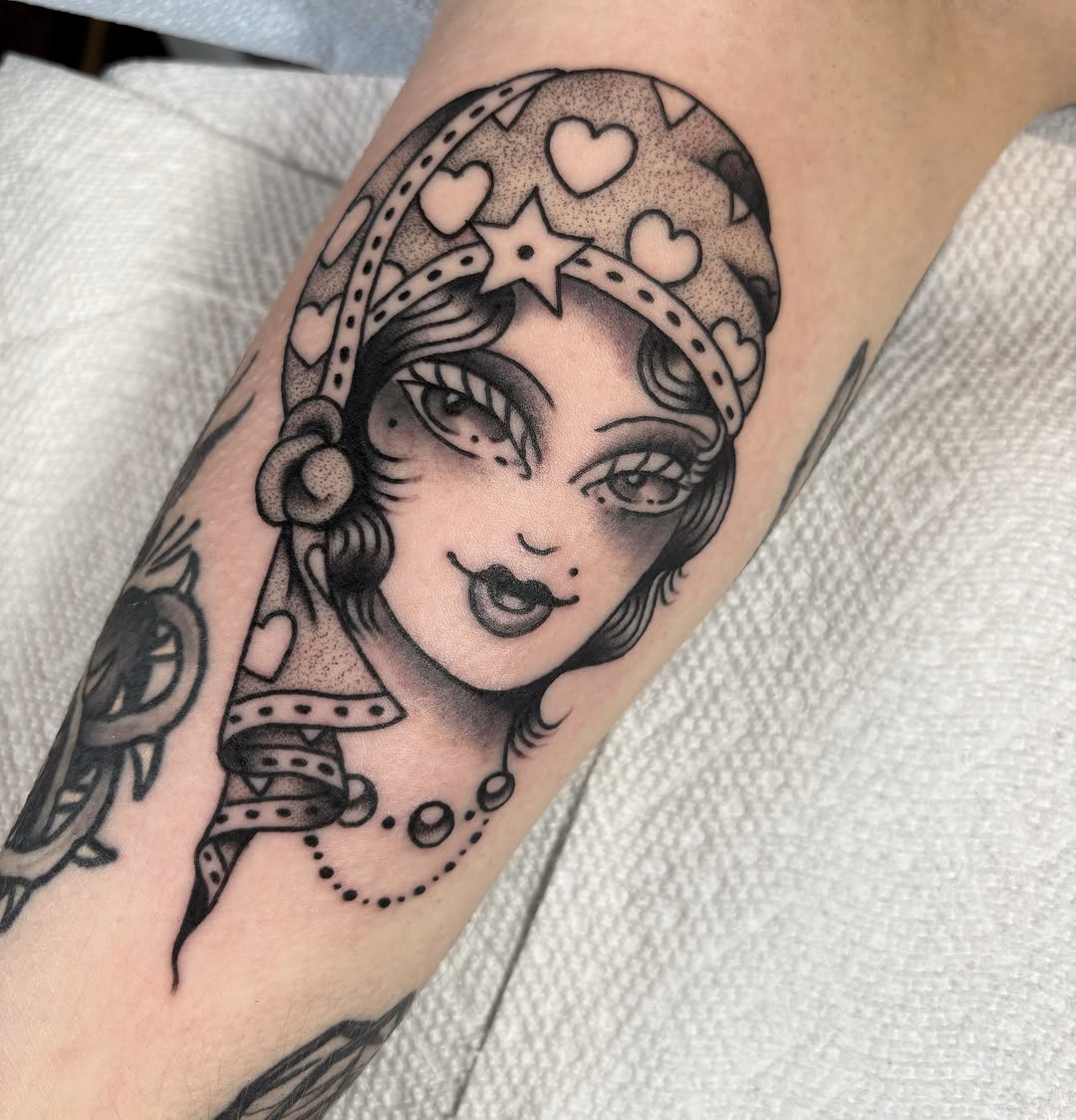 Woman with crown black and grey tattoo on the forearm by Caeli Martin