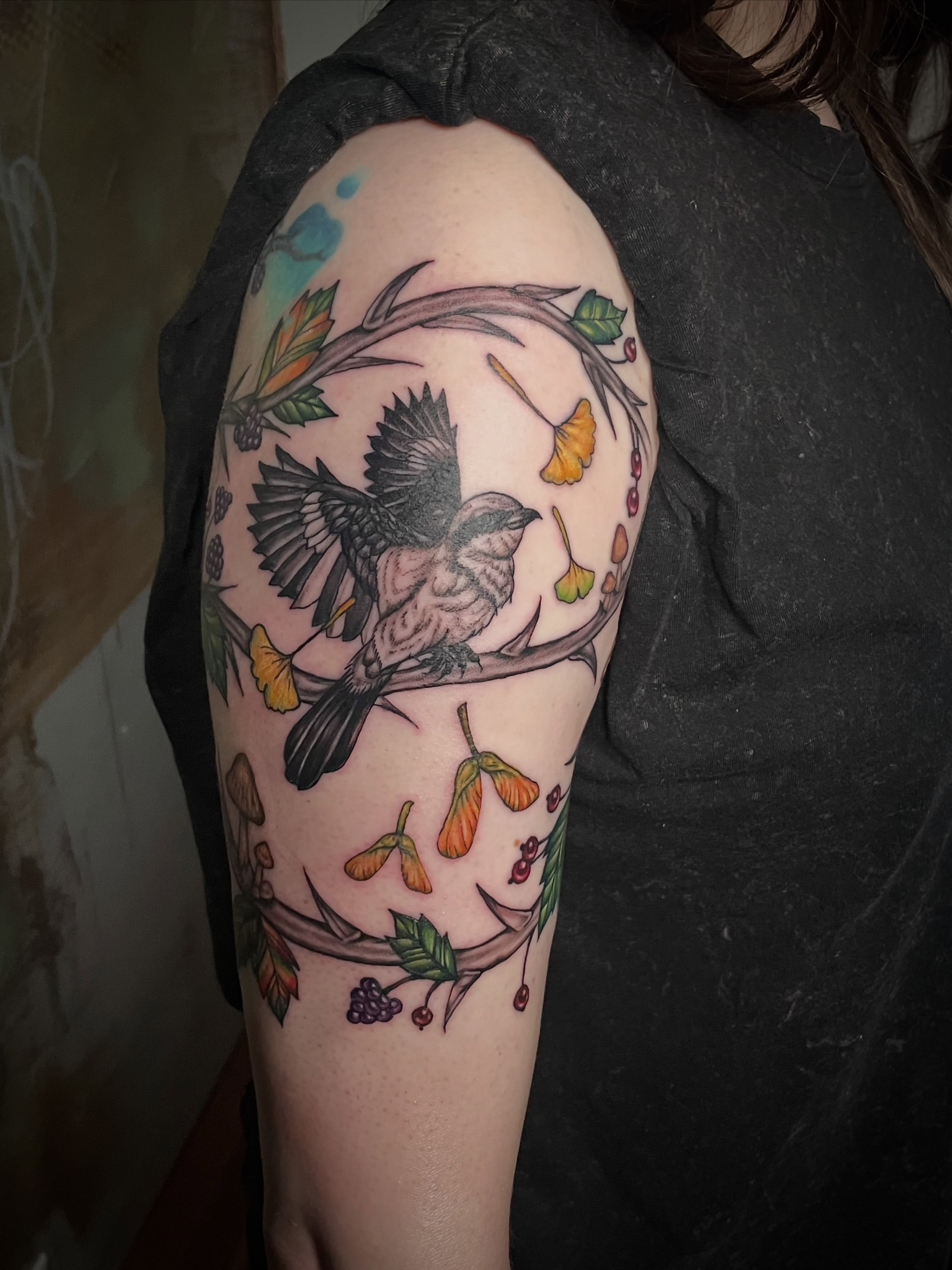 Bird and floral elements neo-traditional tattoo on the upper arm by Hannah Copeskey
