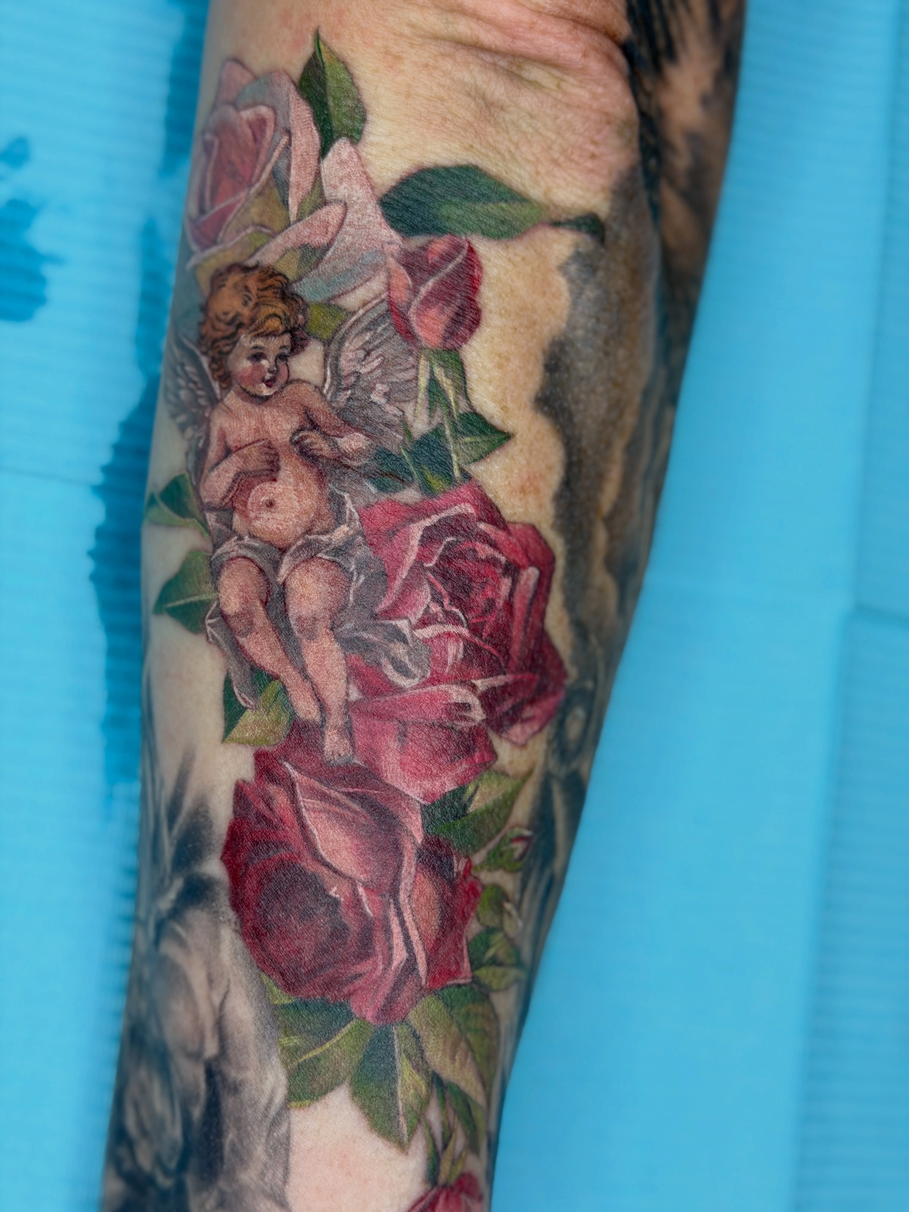 Cherub and roses American traditional tattoo on the forearm by Melissa Rose Moya