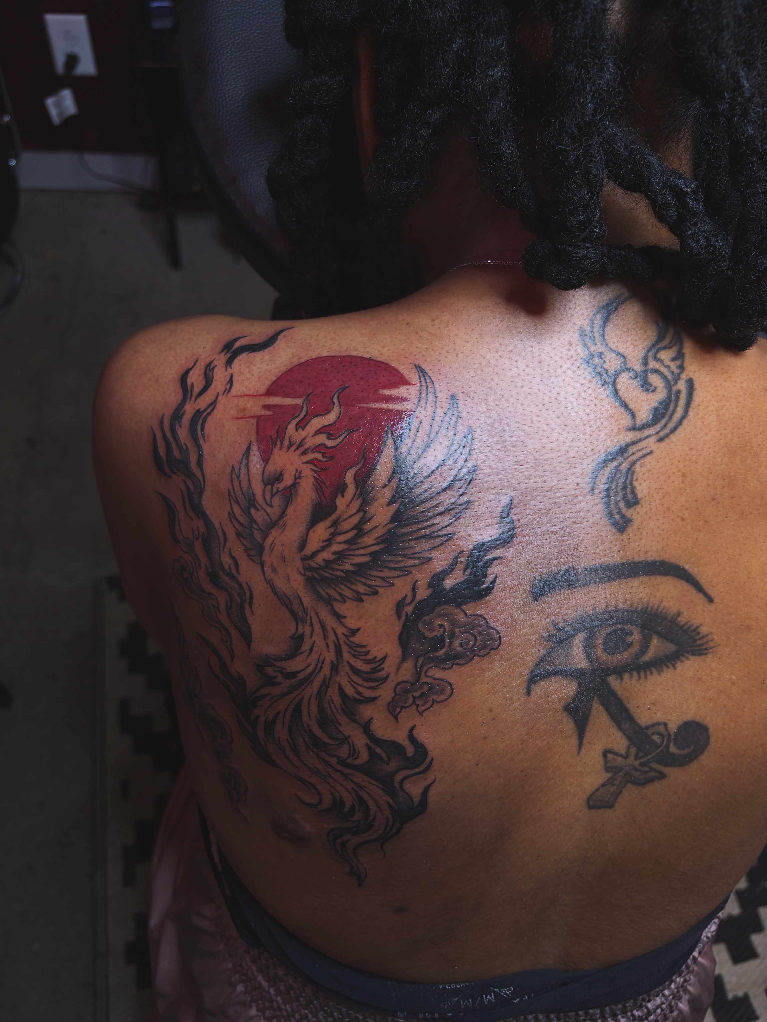 Phoenix and eye black and grey tattoo on the back by ⚜️Embodied Tattoo⚜️, Columbus, Ohio