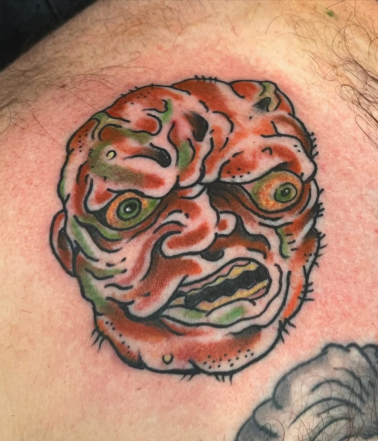 Angry mask American traditional tattoo on the shoulder by Arron Albaugh