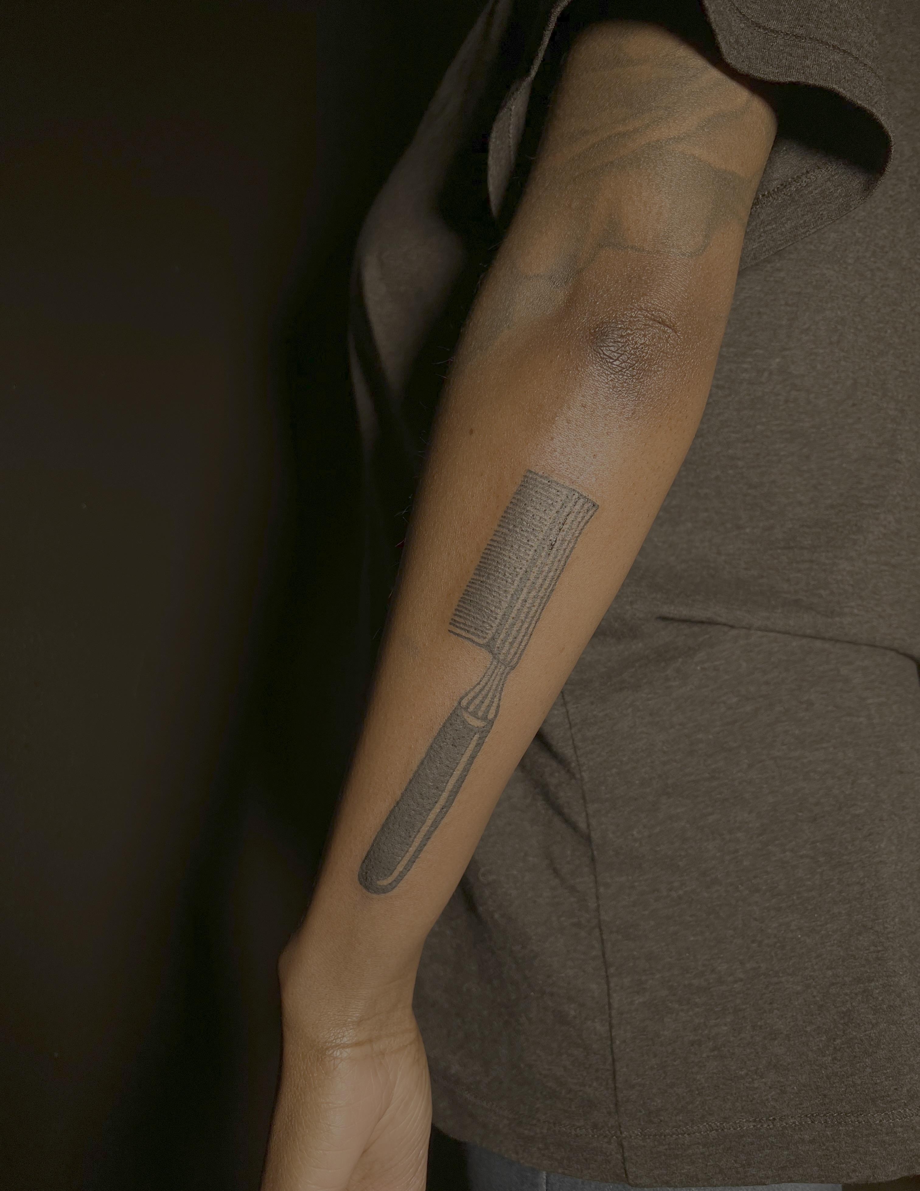 Hairbrush black and grey tattoo on the forearm by V