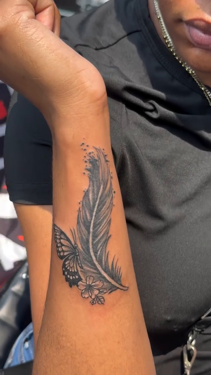 Feather and butterfly lettering tattoo on the forearm by Jose Onasis Disla, New York, New York