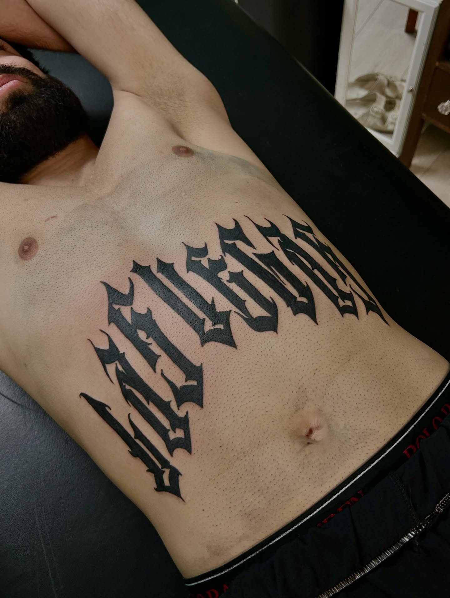 Gothic script tattoo on the chest by Marky