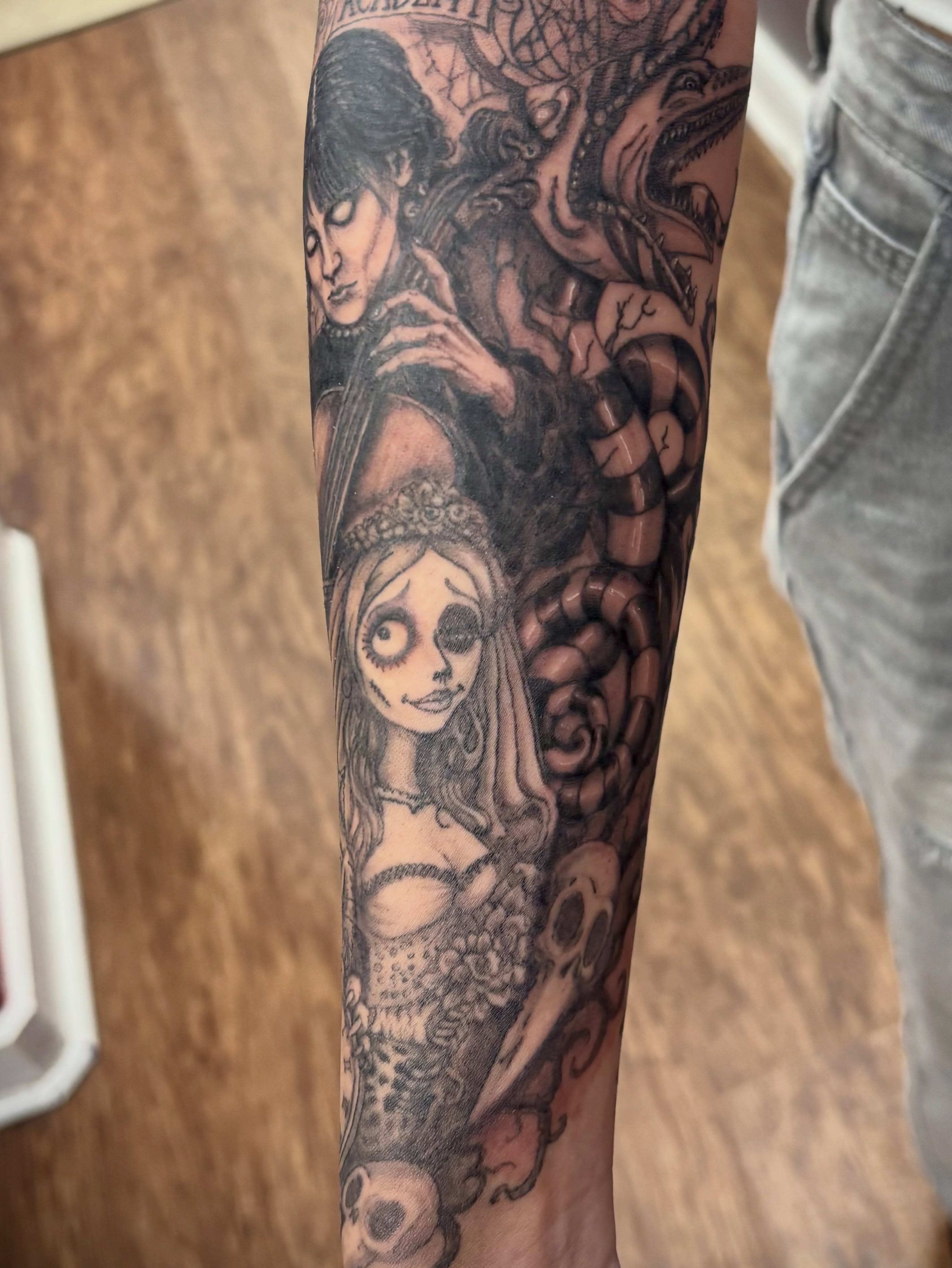 Corpses and skulls dark realism tattoo on the forearm by Thom Johns-Green