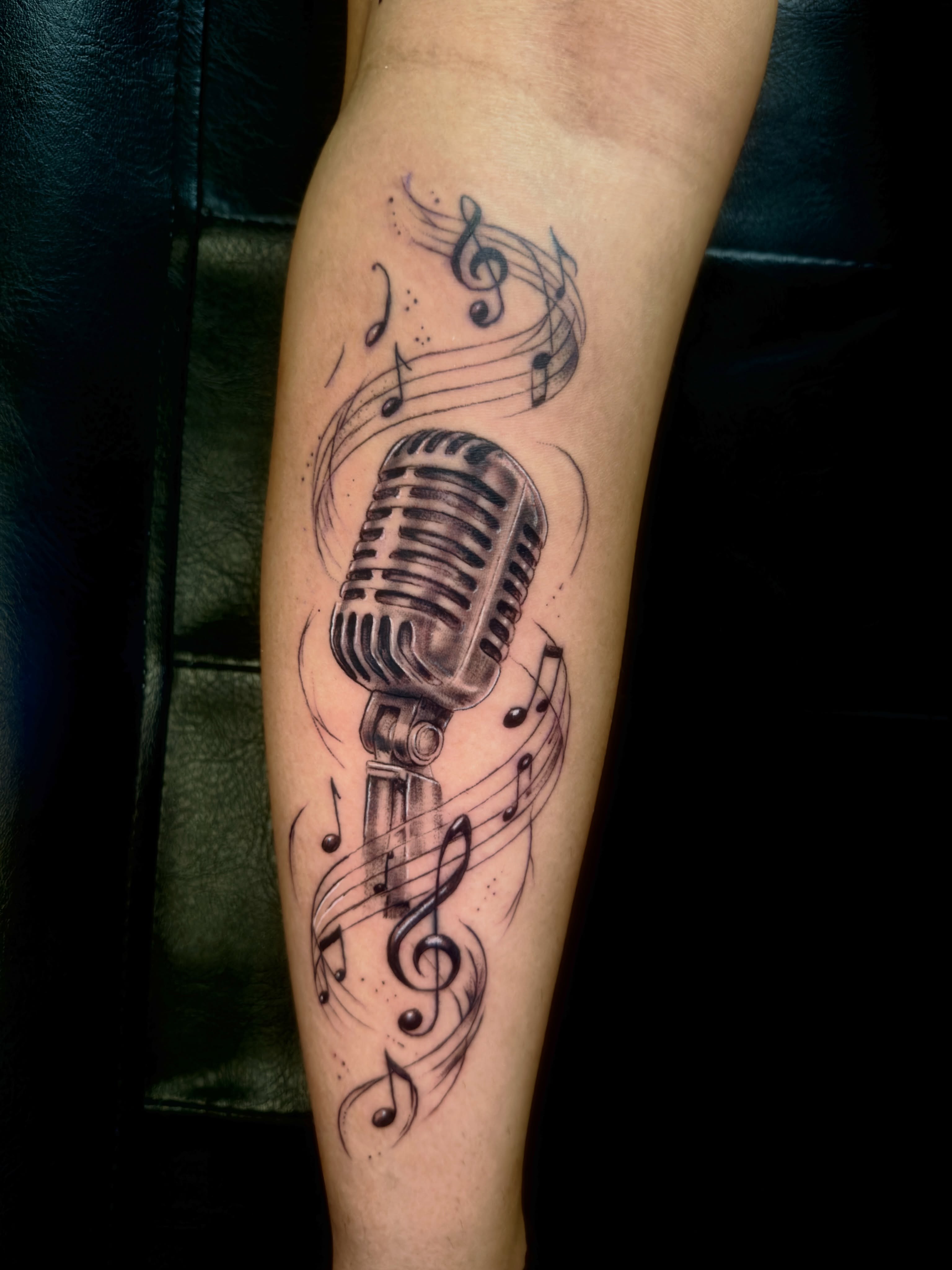 Microphone and musical notes realism tattoo on the forearm by Caloy Obra