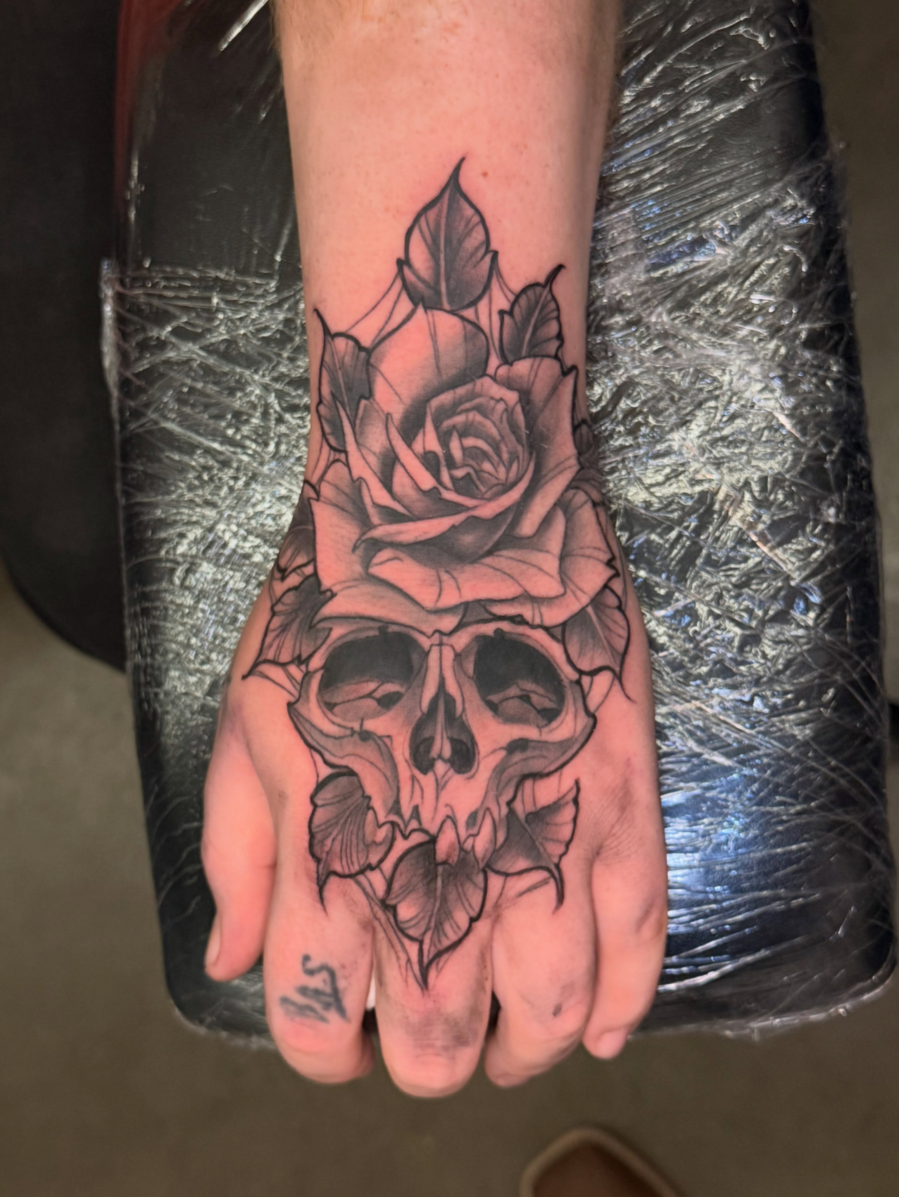 Skull with rose black and grey tattoo on the hand by InkdByHendrixx