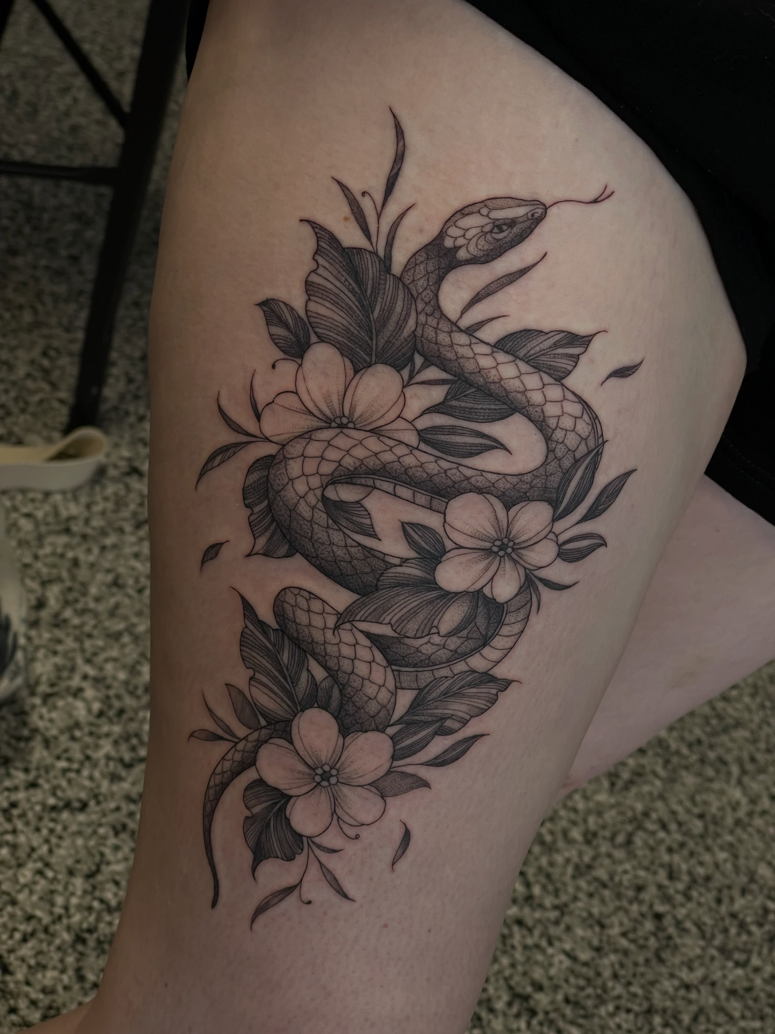 Snake and flowers realism tattoo on the thigh by Jonathan Red