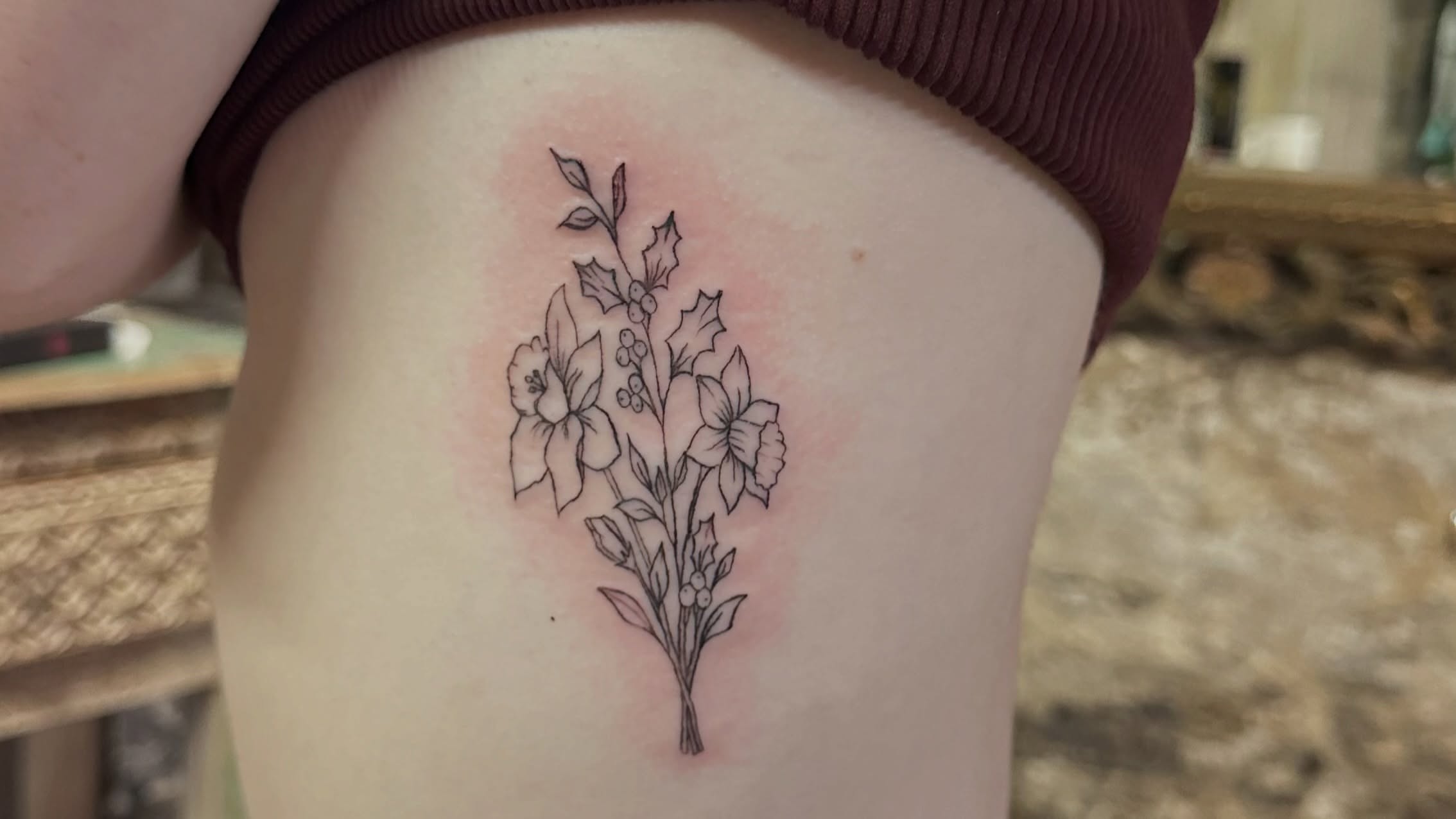 Daffodils and holly black and grey tattoo on the thigh by Lunette : a little moon as simple as that
