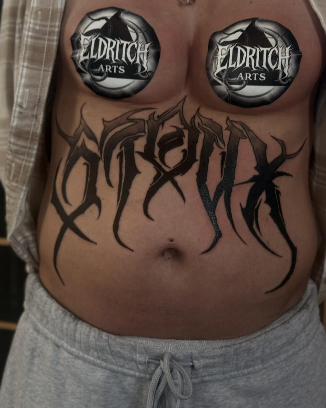 Gothic script black and grey tattoo on the torso by Miles Haysmith