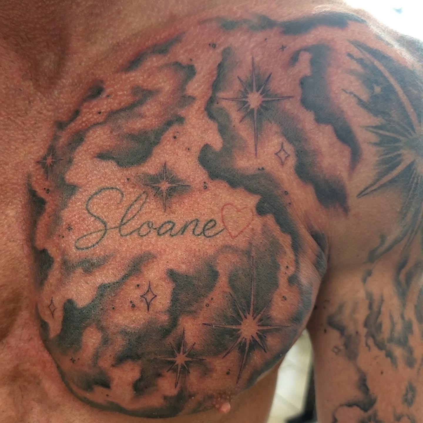 Name with stars black and grey tattoo on the chest by Ian Duncanson