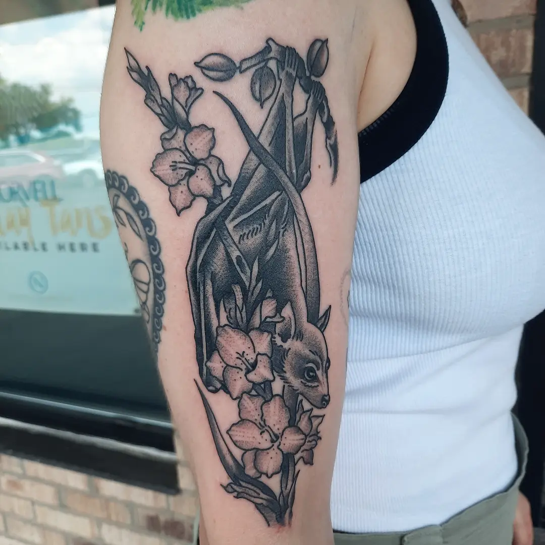 Bat and flowers realism tattoo on the forearm by Kaetlyn