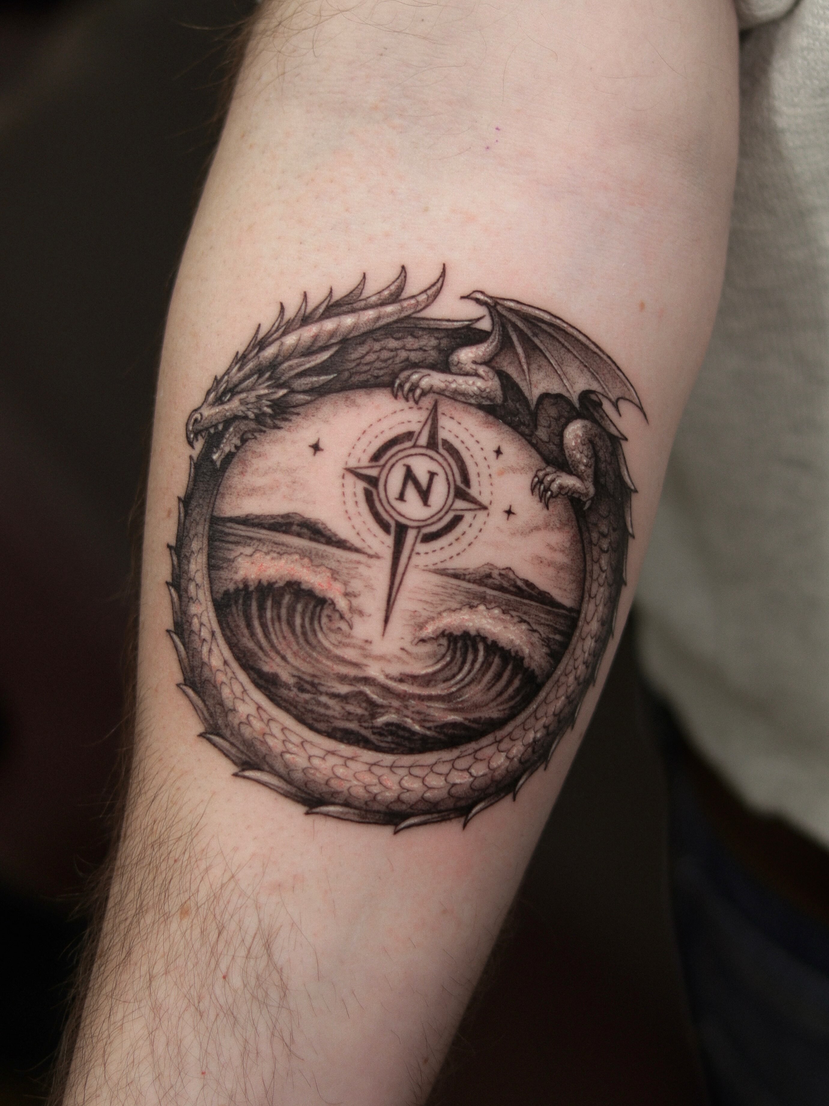 Dragon and compass realism tattoo on the forearm by Arthur Kossoski