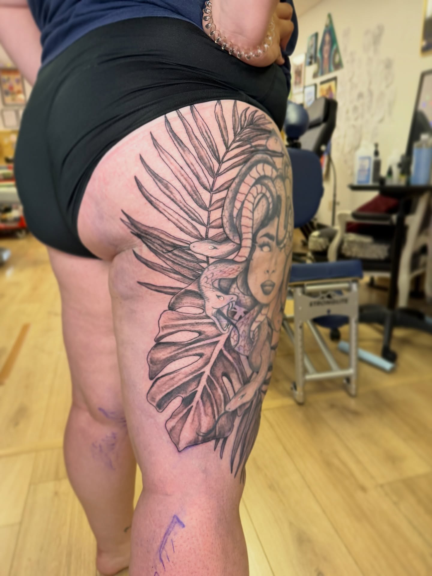 Woman with tropical leaves realism tattoo on the thigh by Dani Fried Tattoos