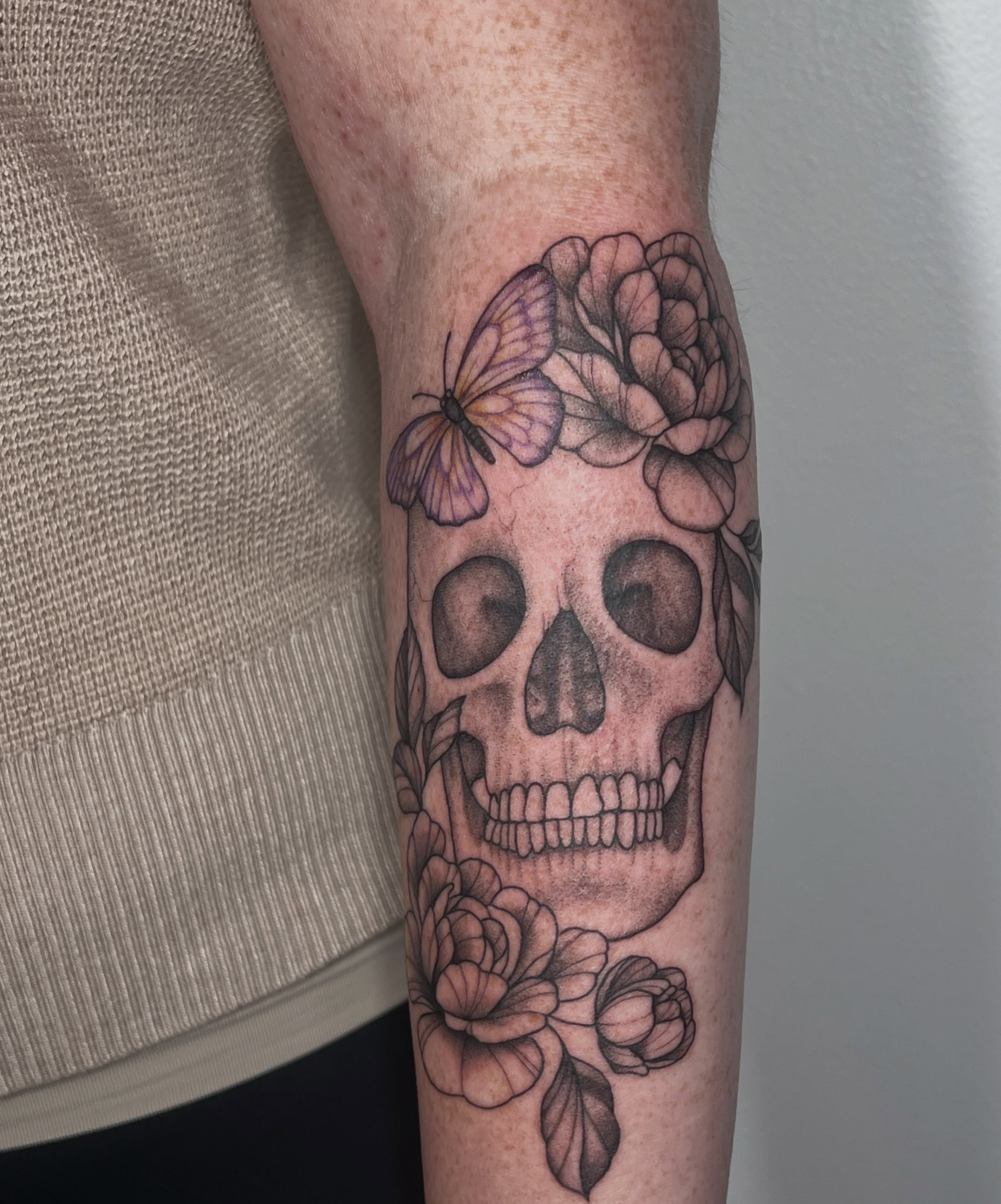 Skull with flowers and butterfly realism tattoo on the forearm by Presley Tattoos, Murfreesboro, Tennessee