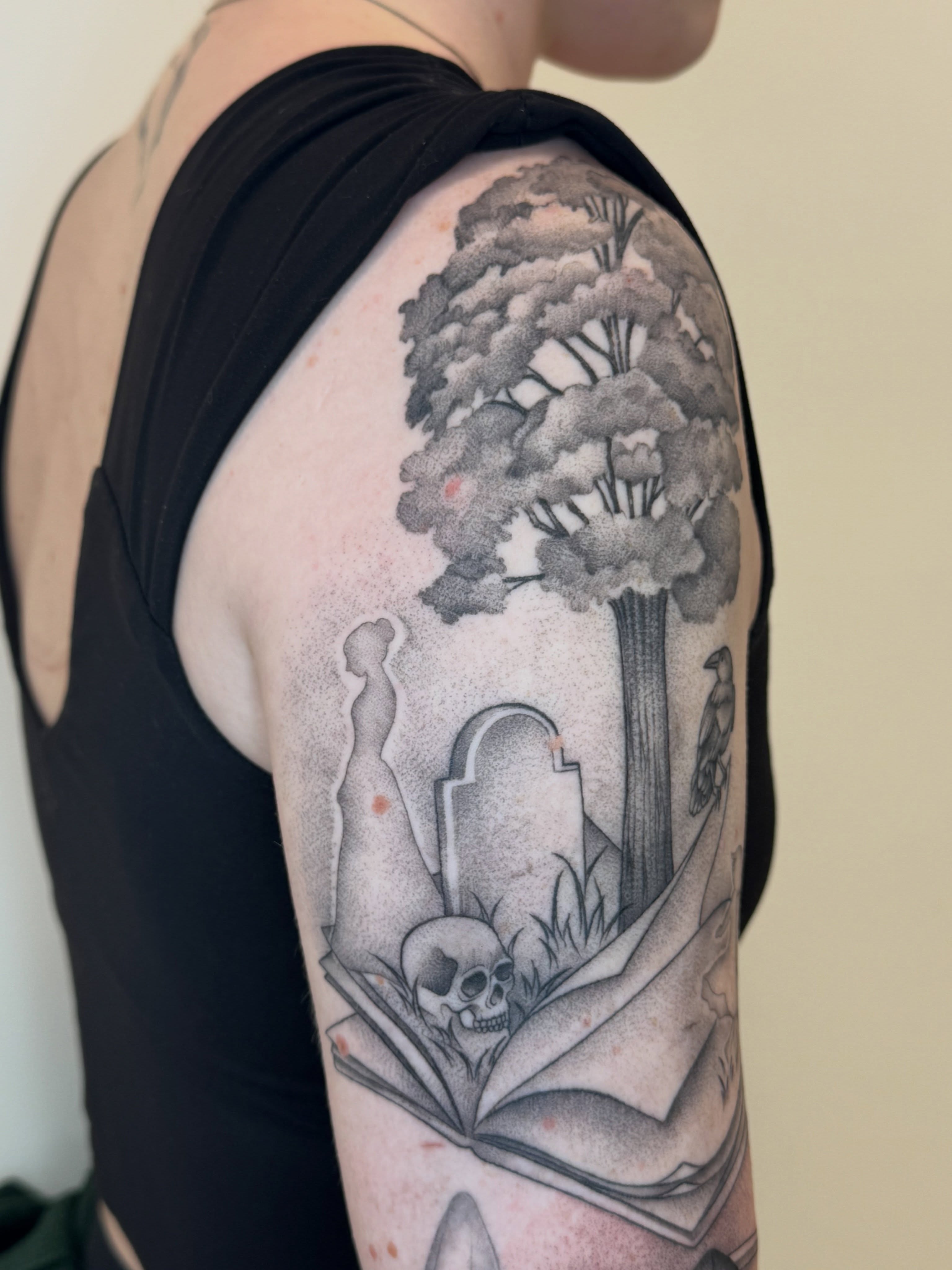 Book with skull and tombstone dotwork tattoo on the upper arm by Tara Crespi - Female Tattoo Artist 💜