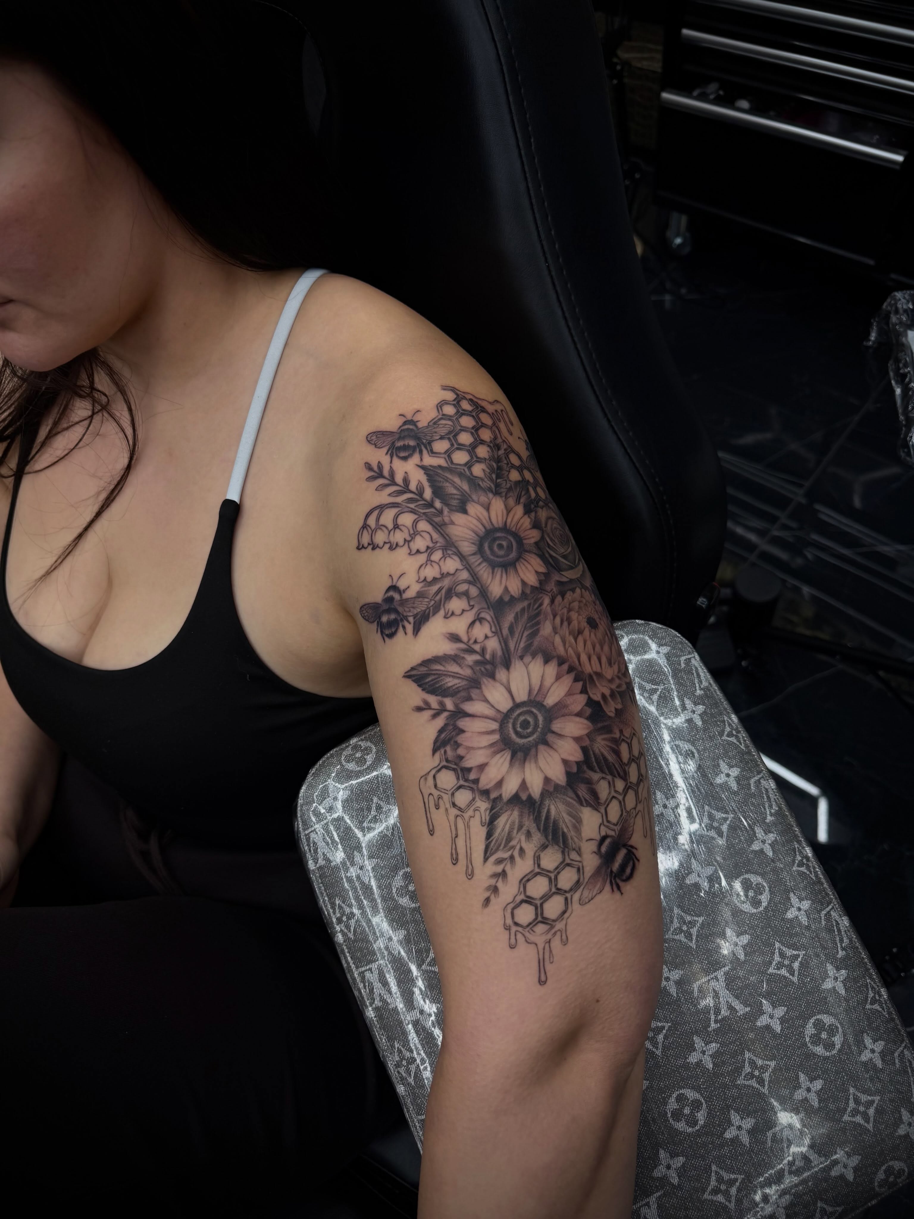 Sunflowers and bees realism tattoo on the upper arm by Amber Lynn