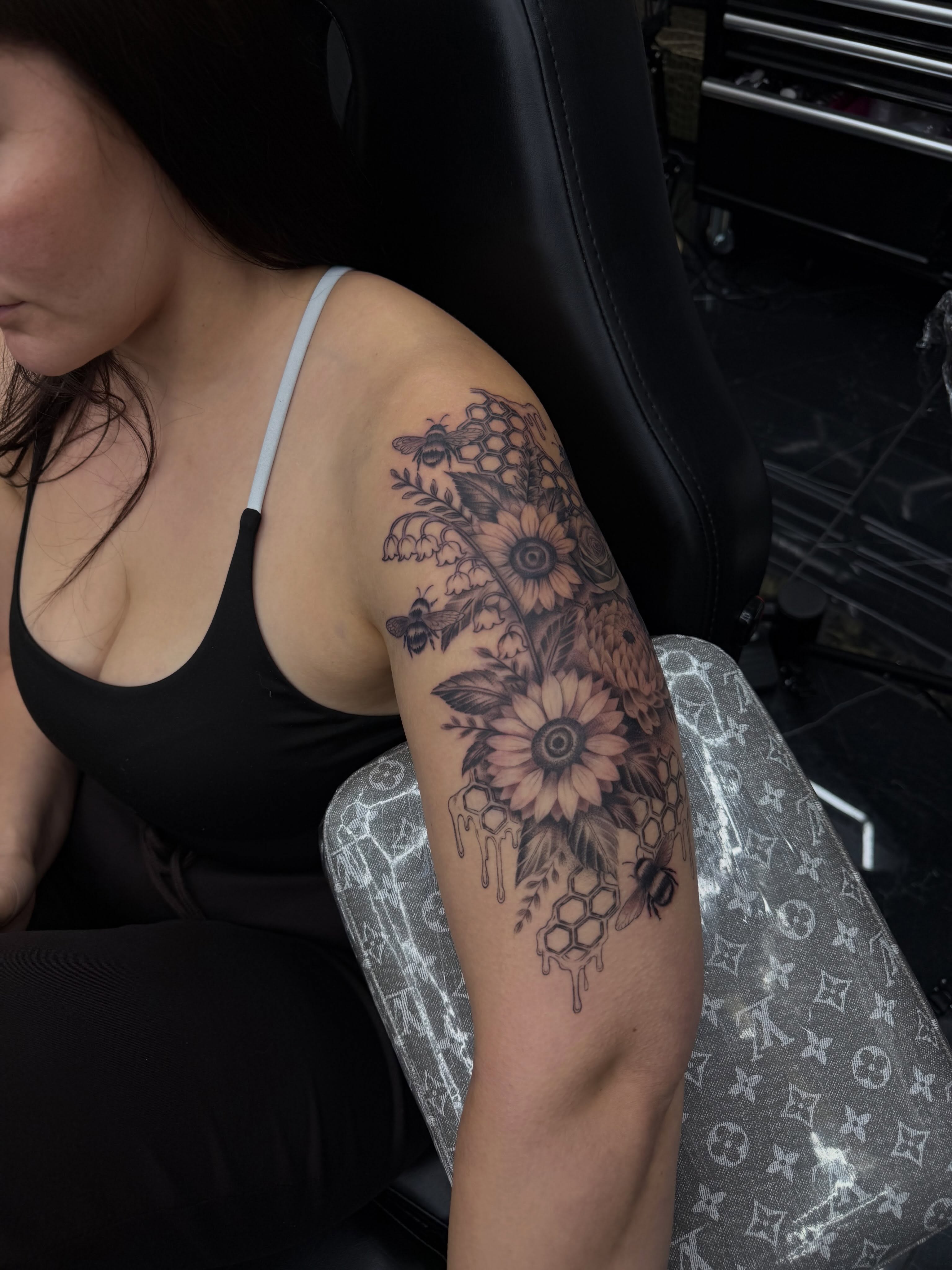 Sunflower and bees realism tattoo on the upper arm by Amber Lynn