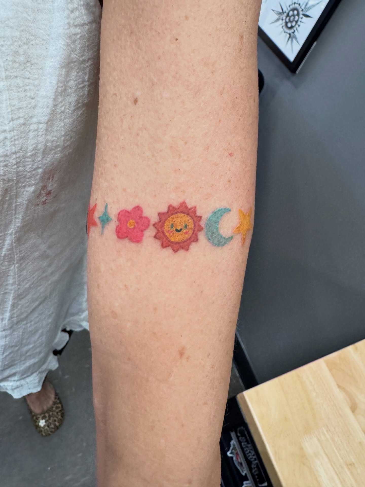 Sun, flower, moon, stars new school tattoo on the forearm by Samantha Jane