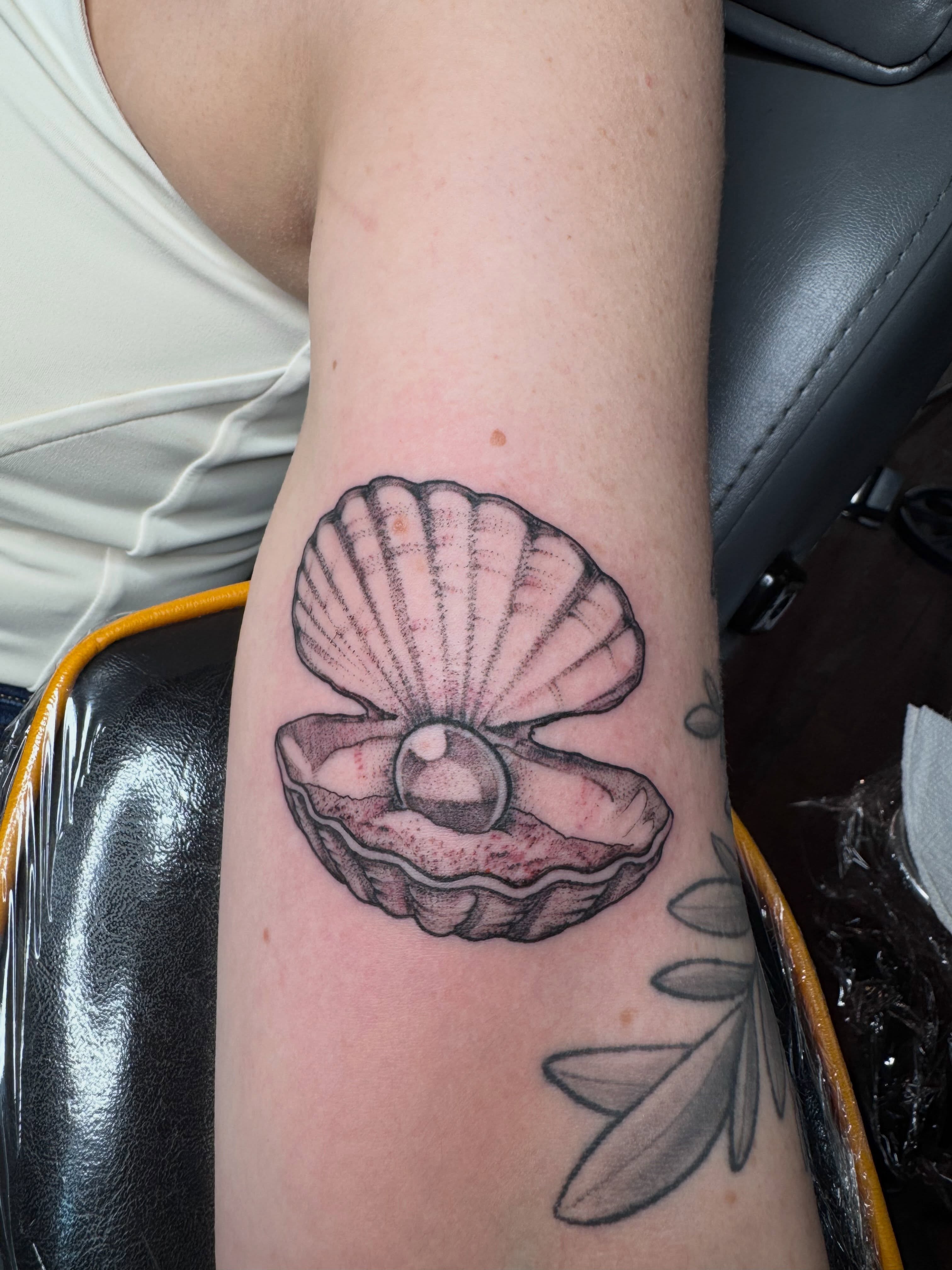 Shell with pearl black and grey tattoo on the forearm by 🏵