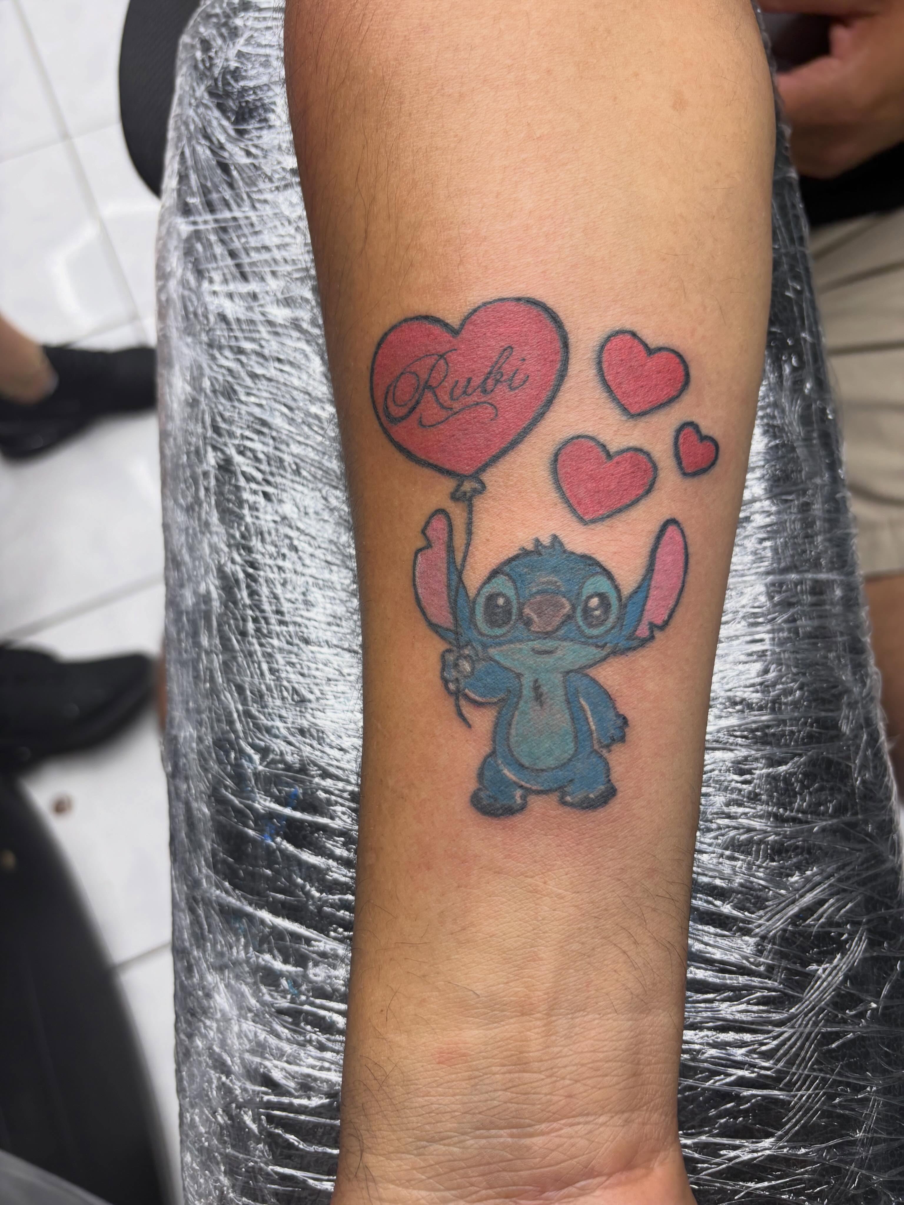 Stitch with heart balloon anime tattoo on the forearm by Shadows Tattoos