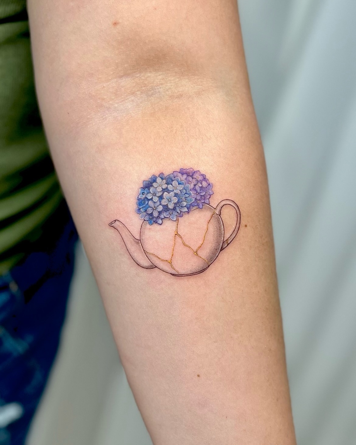 Teapot with hydrangea dotwork tattoo on the forearm by Soy 🫛