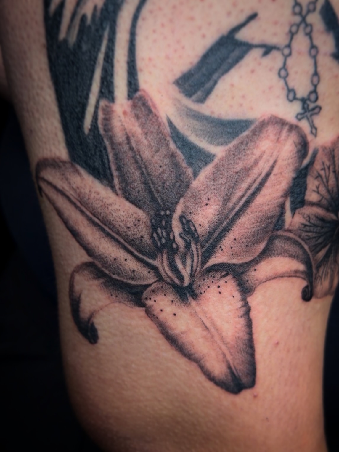 Lily dotwork tattoo on the upper arm by Aaron Strobehn