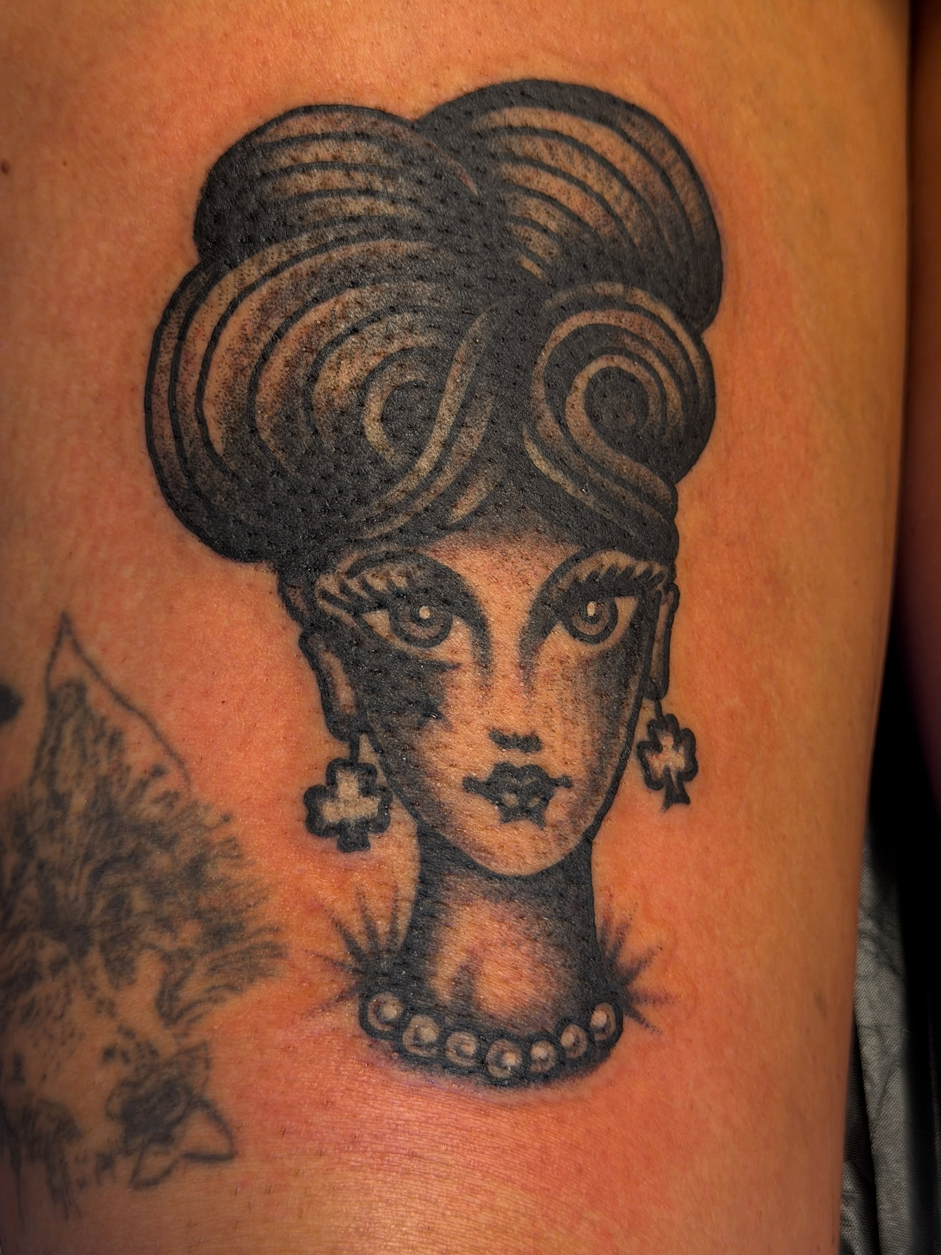 Woman with elaborate hairstyle black and grey tattoo on the thigh by Joshua Speight