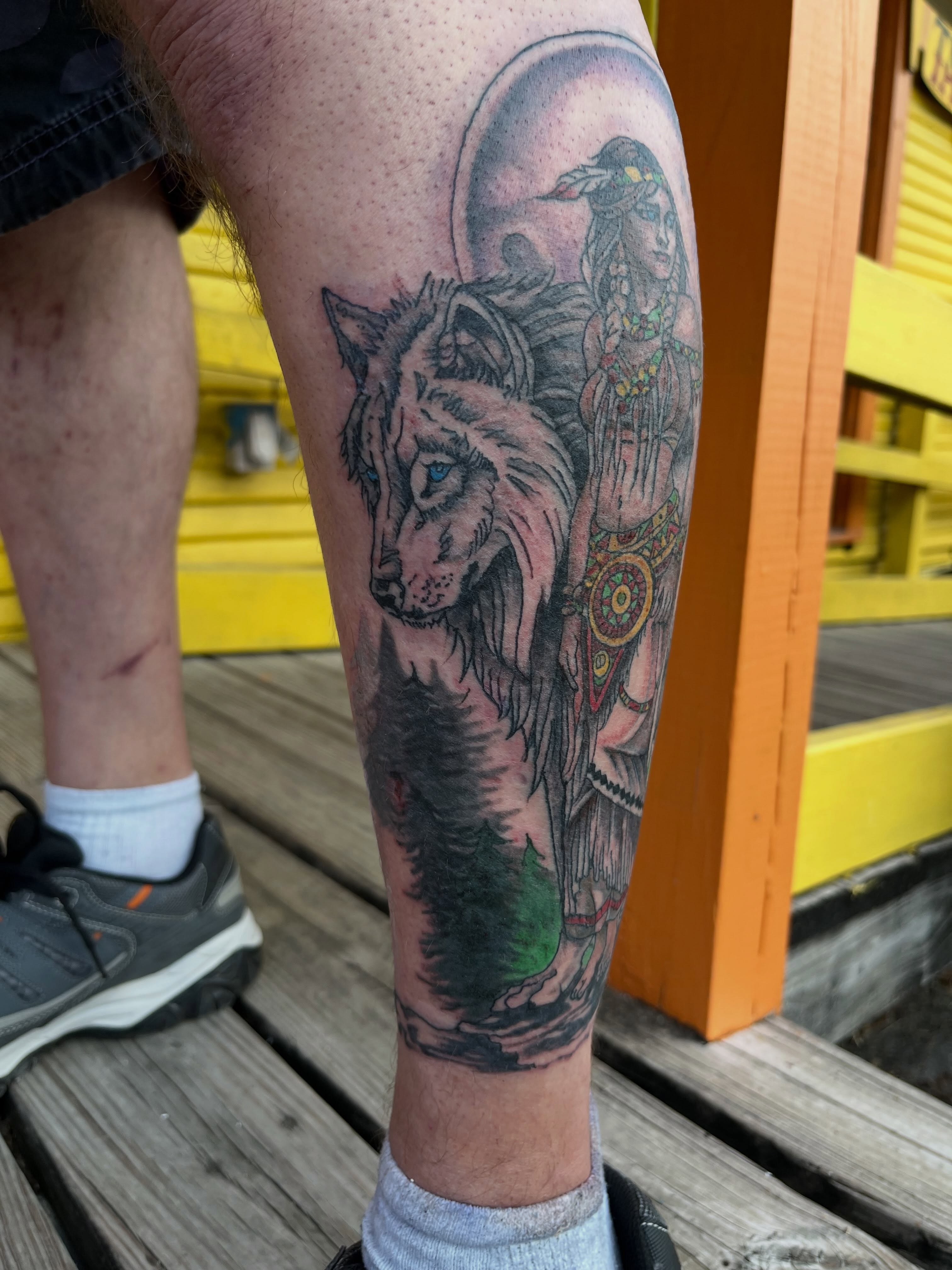 Wolf and native figure realism tattoo on the calf by Roachrude