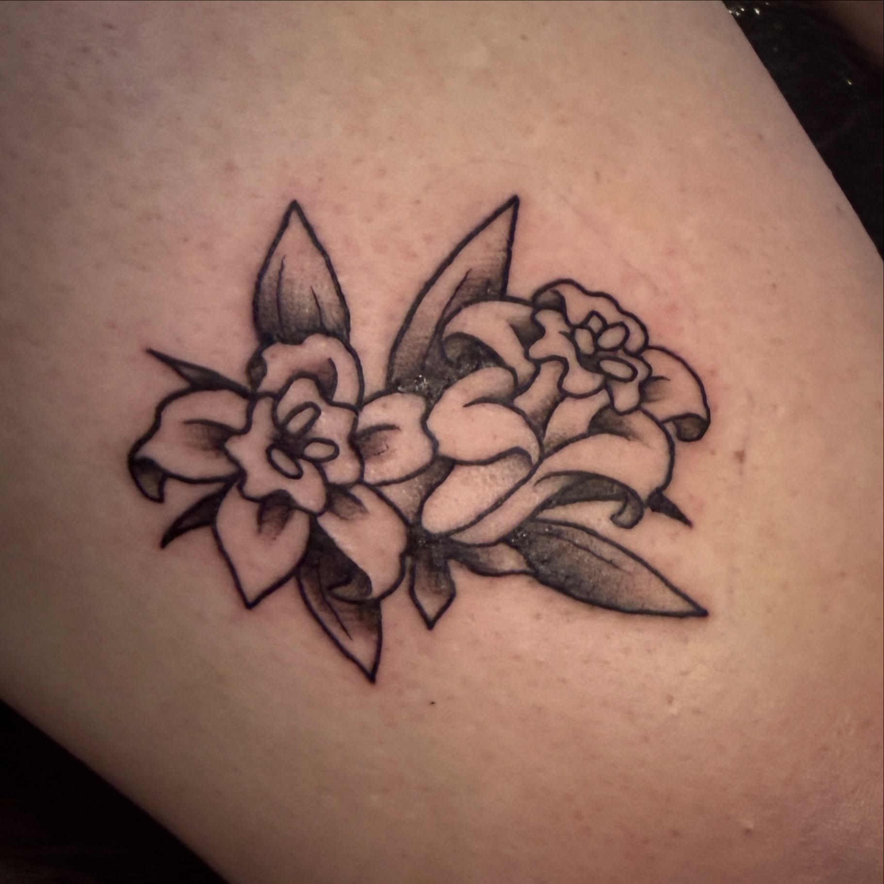 Flowers black and grey tattoo on the thigh by Luisa Gonzalez, Austin, Texas