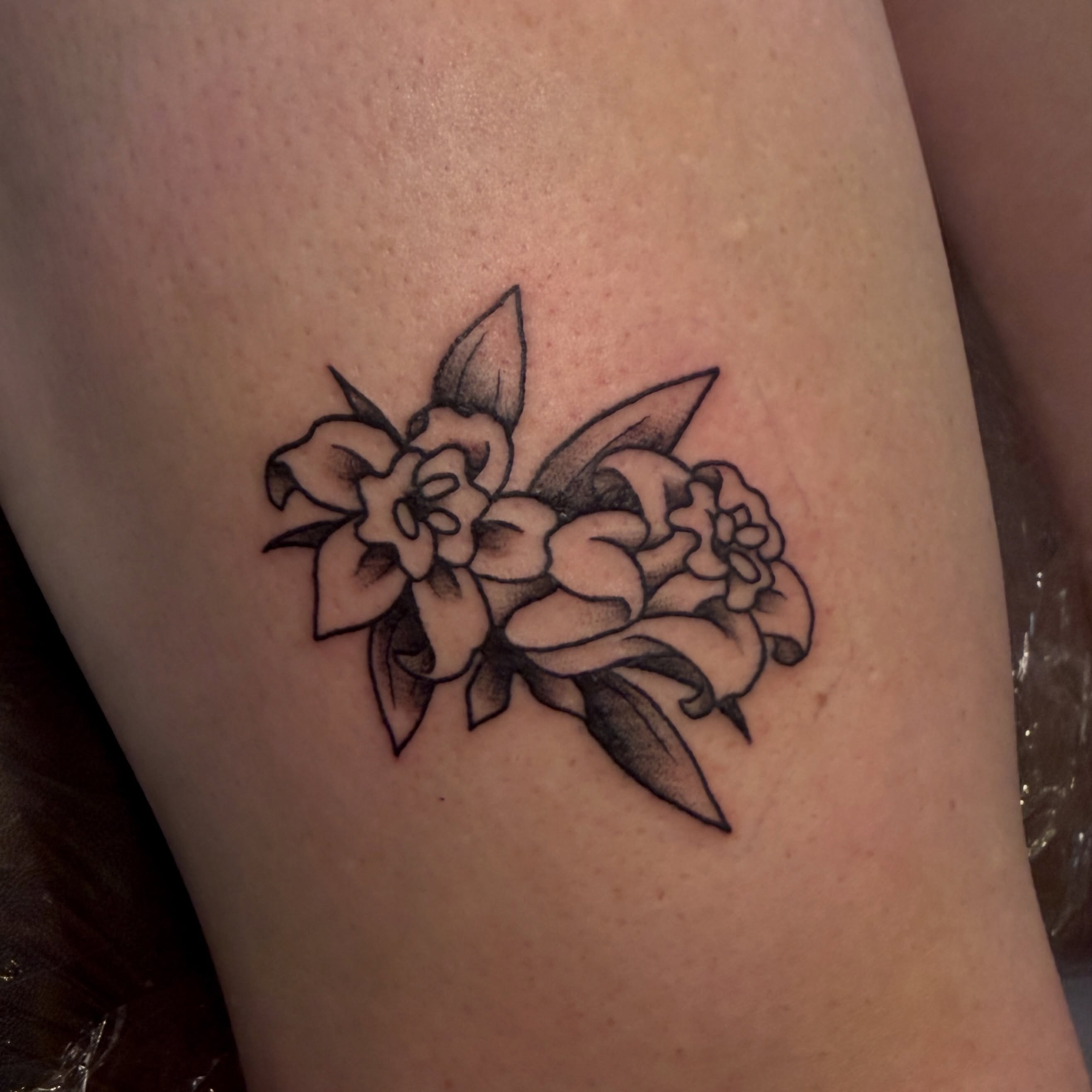 Flowers black and grey tattoo on the thigh by Luisa Gonzalez, Austin, Texas