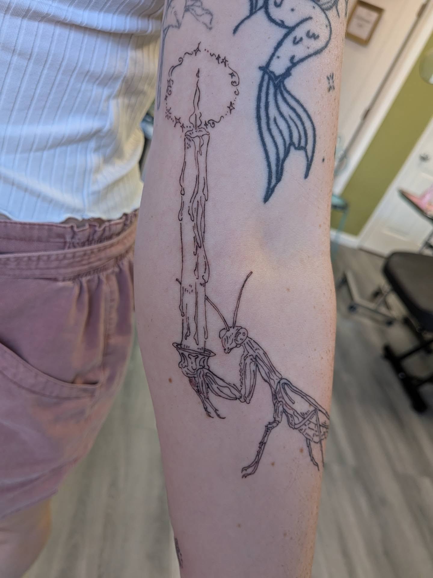 Praying mantis and candle black and grey tattoo on the forearm by Ryan