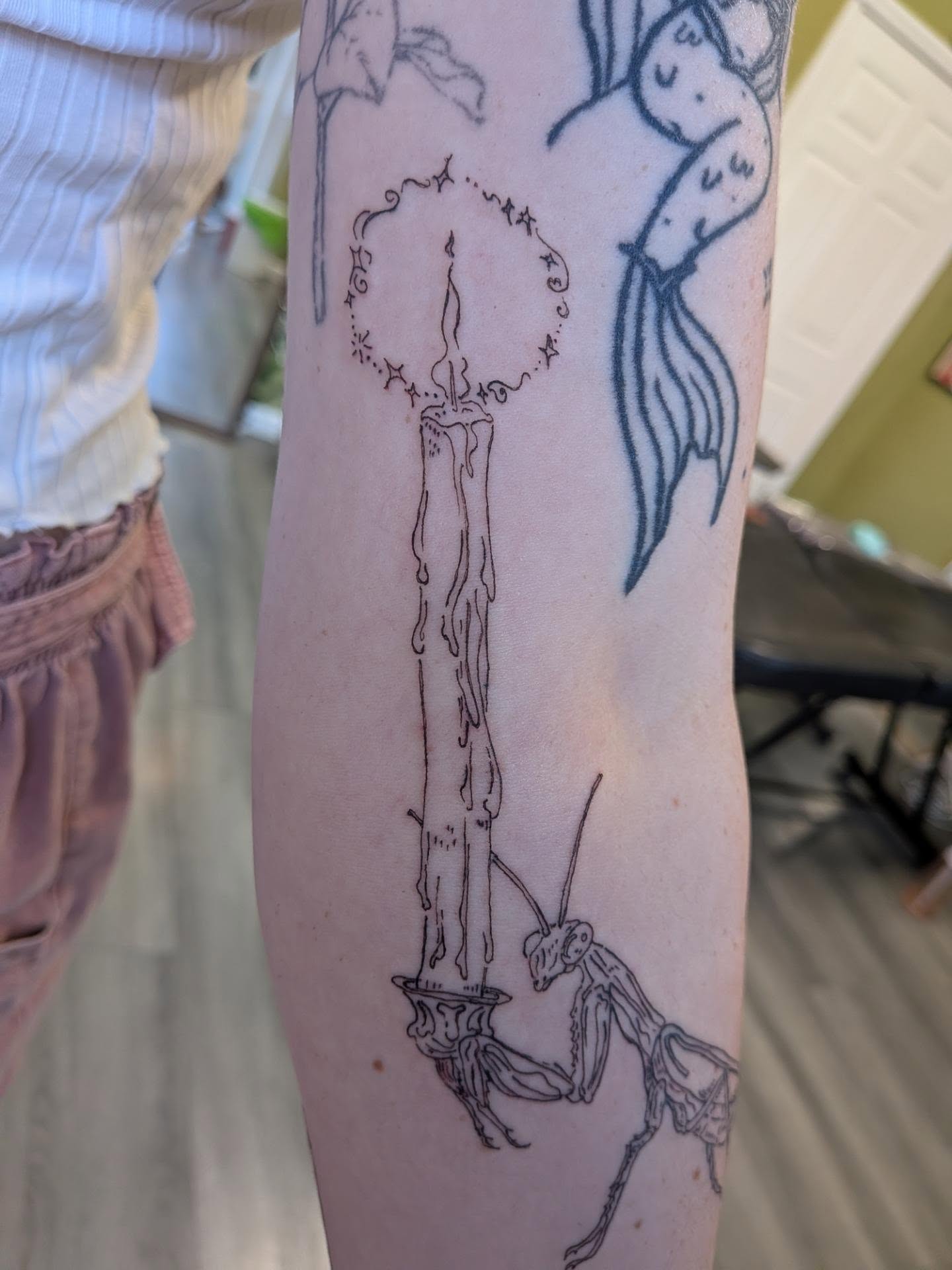 Candle and mantis black and grey tattoo on the forearm by Ryan