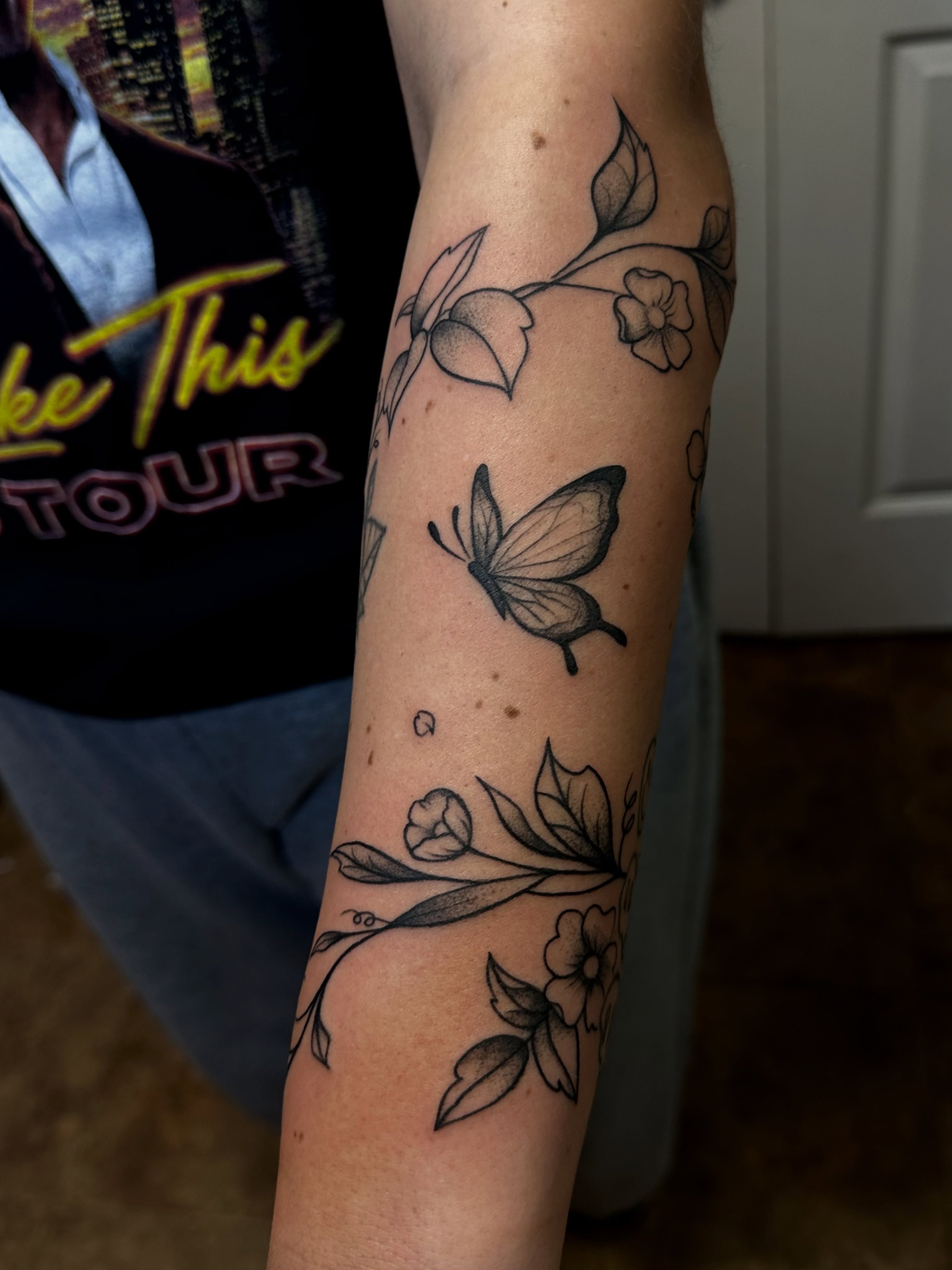 Butterfly and floral black and grey tattoo on the forearm by Jocelyn