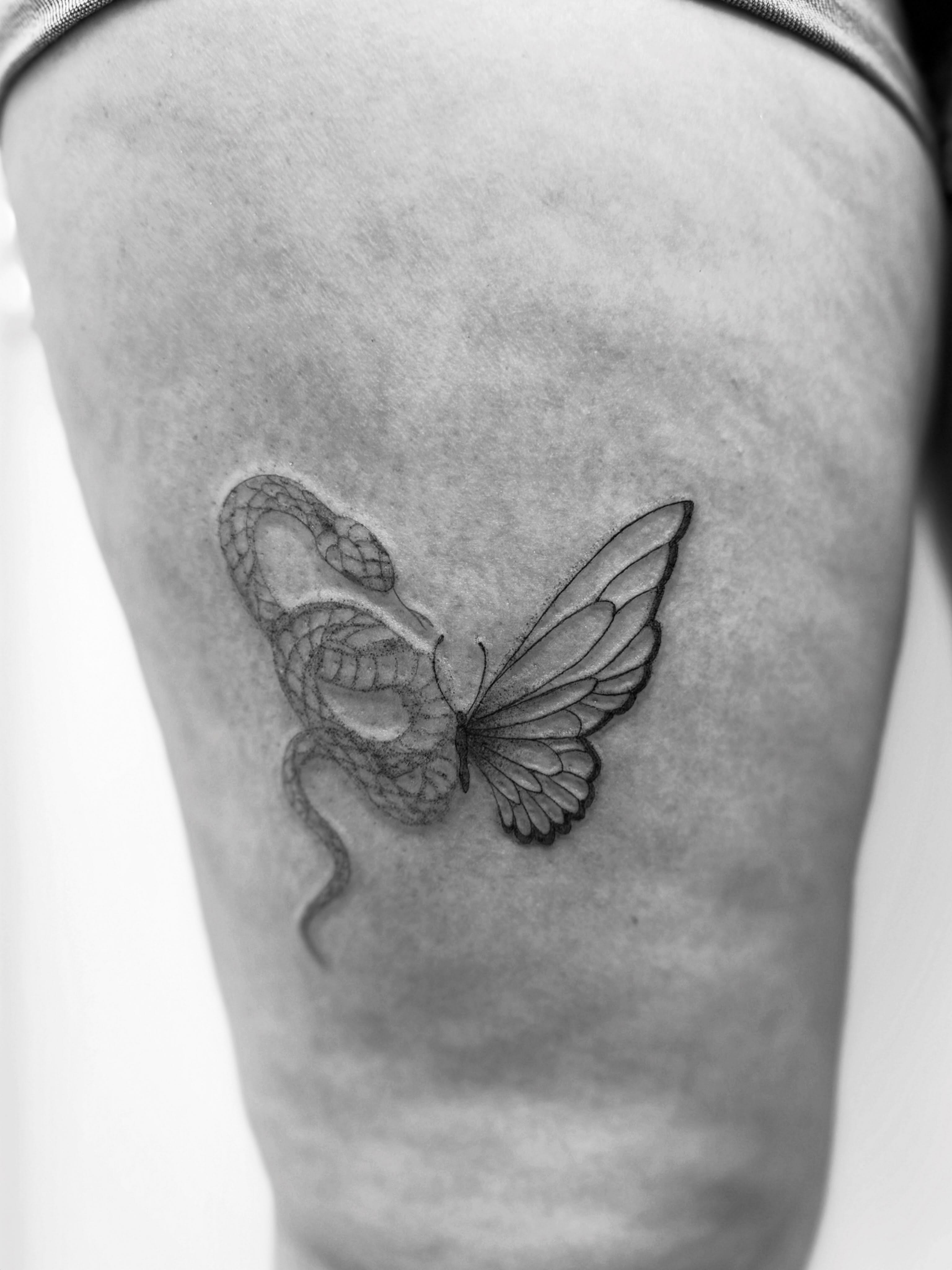 Butterfly and snake black and grey tattoo on the thigh by Taylor Johnson