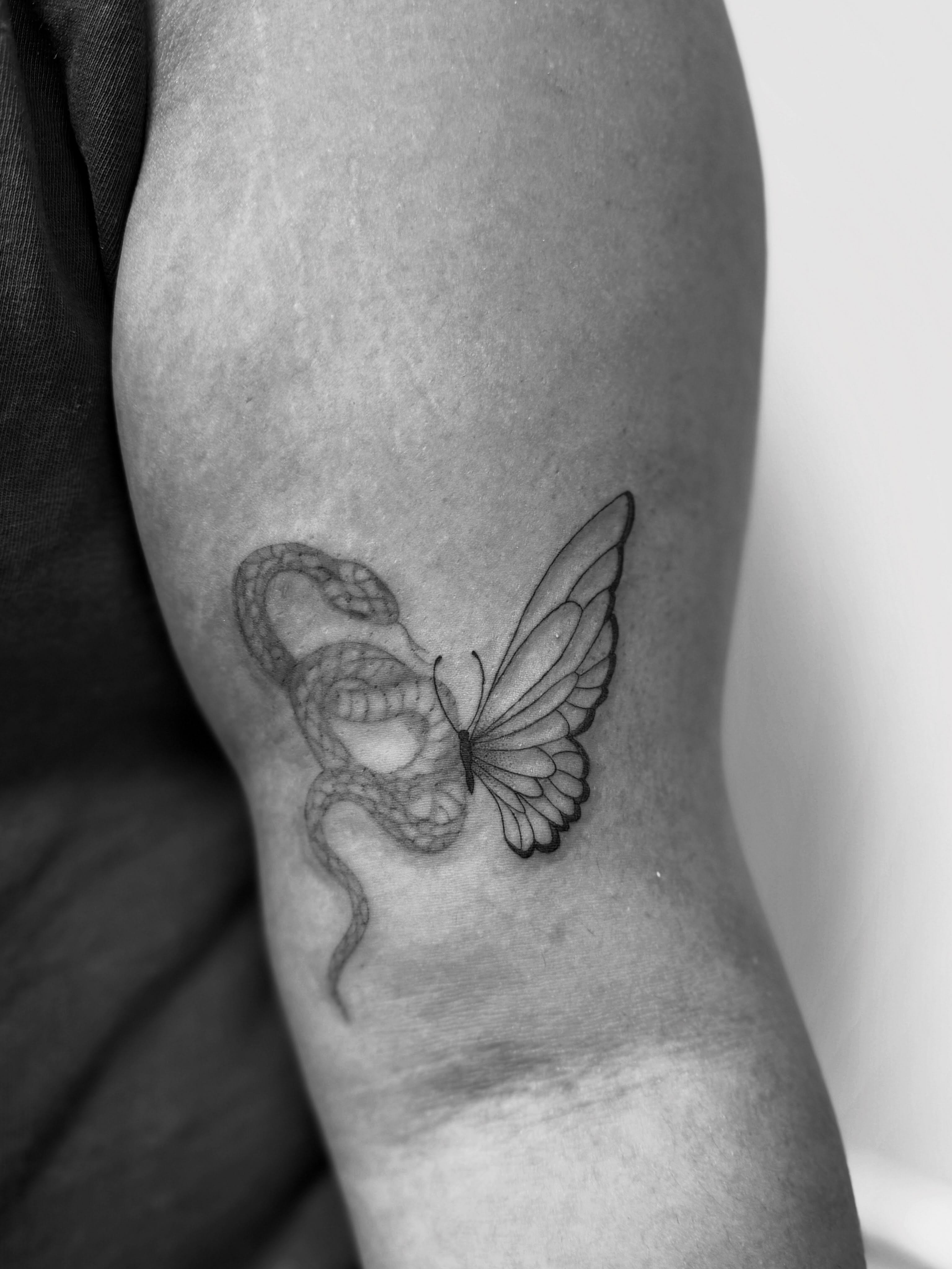 Snake and butterfly black and grey tattoo on the forearm by Taylor Johnson