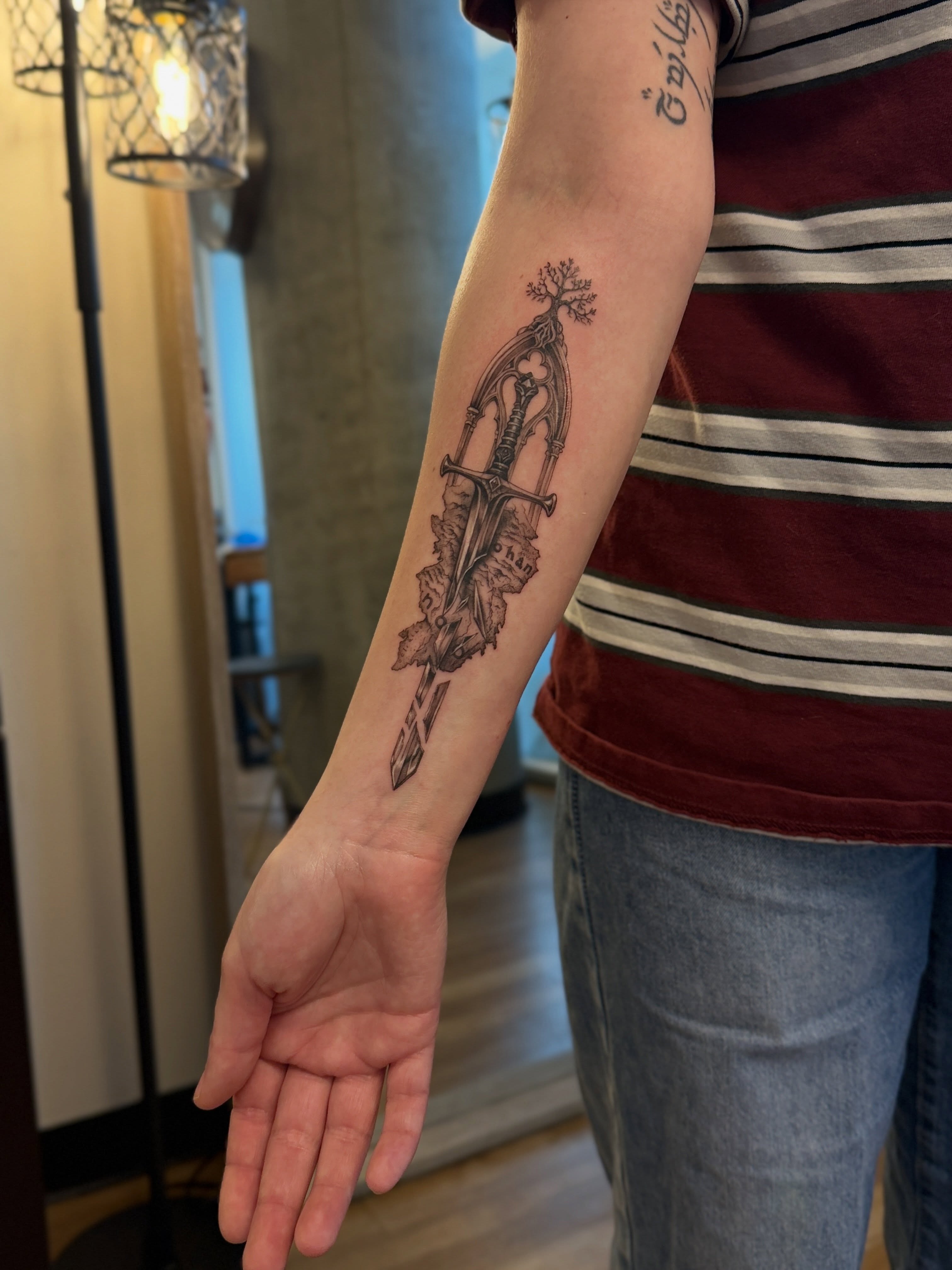 Sword and tree black and grey tattoo on the forearm by Aristova Anastasia