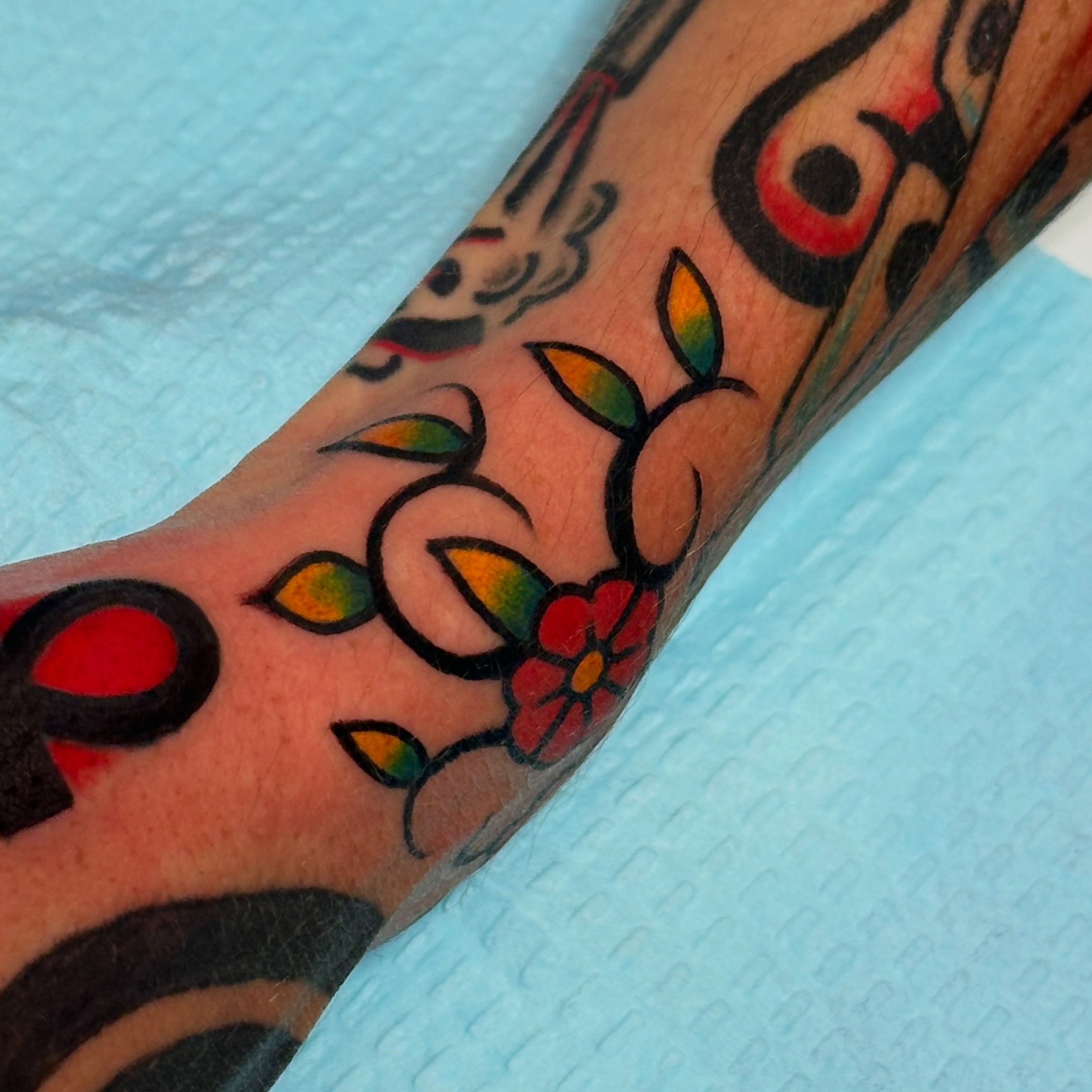 Flower and leaves American traditional tattoo on the forearm by Kiki Painmaker Trad Tattooer 🧨