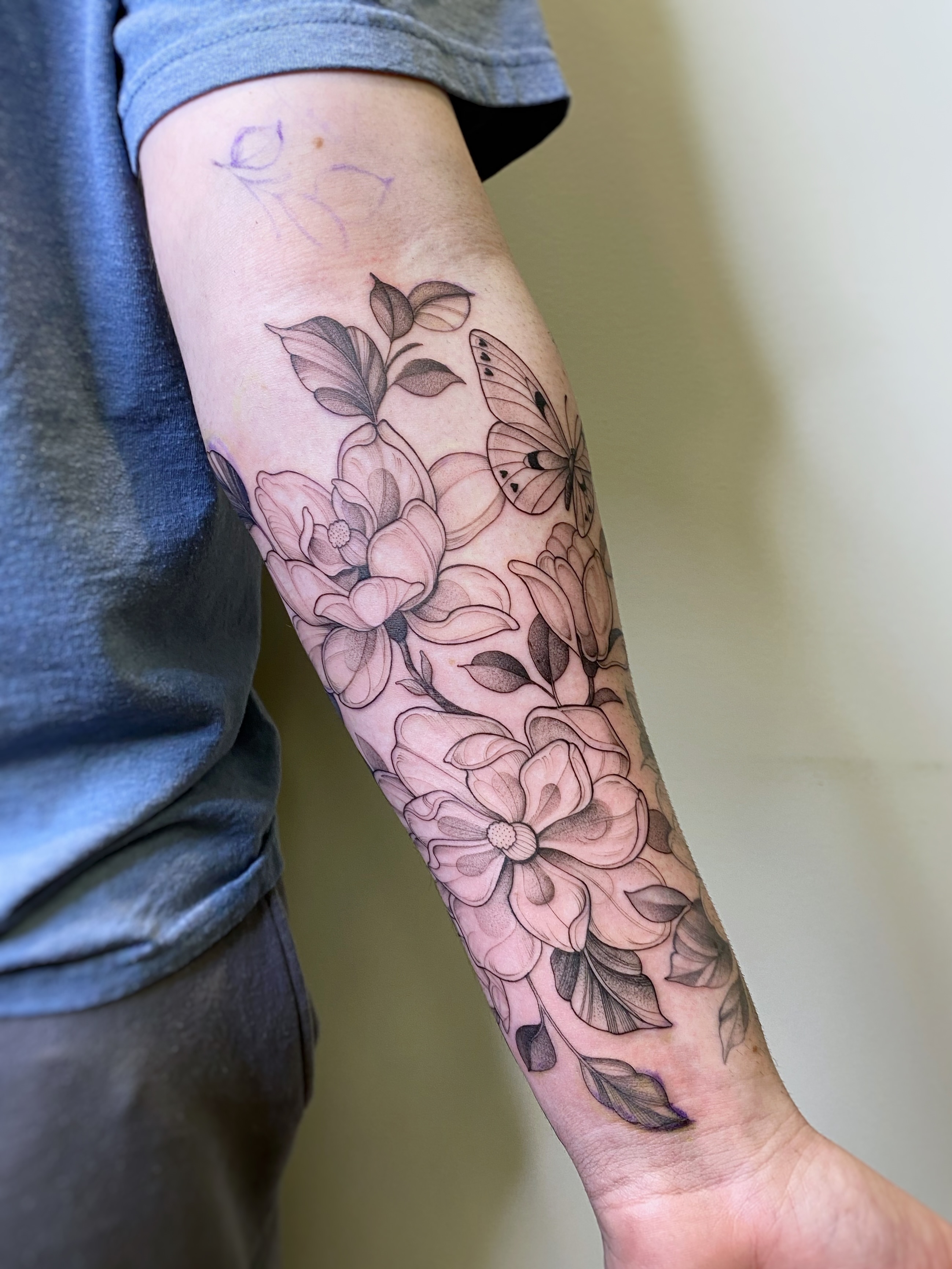 Flowers and butterfly black and grey tattoo on the forearm by Caitlin Watters