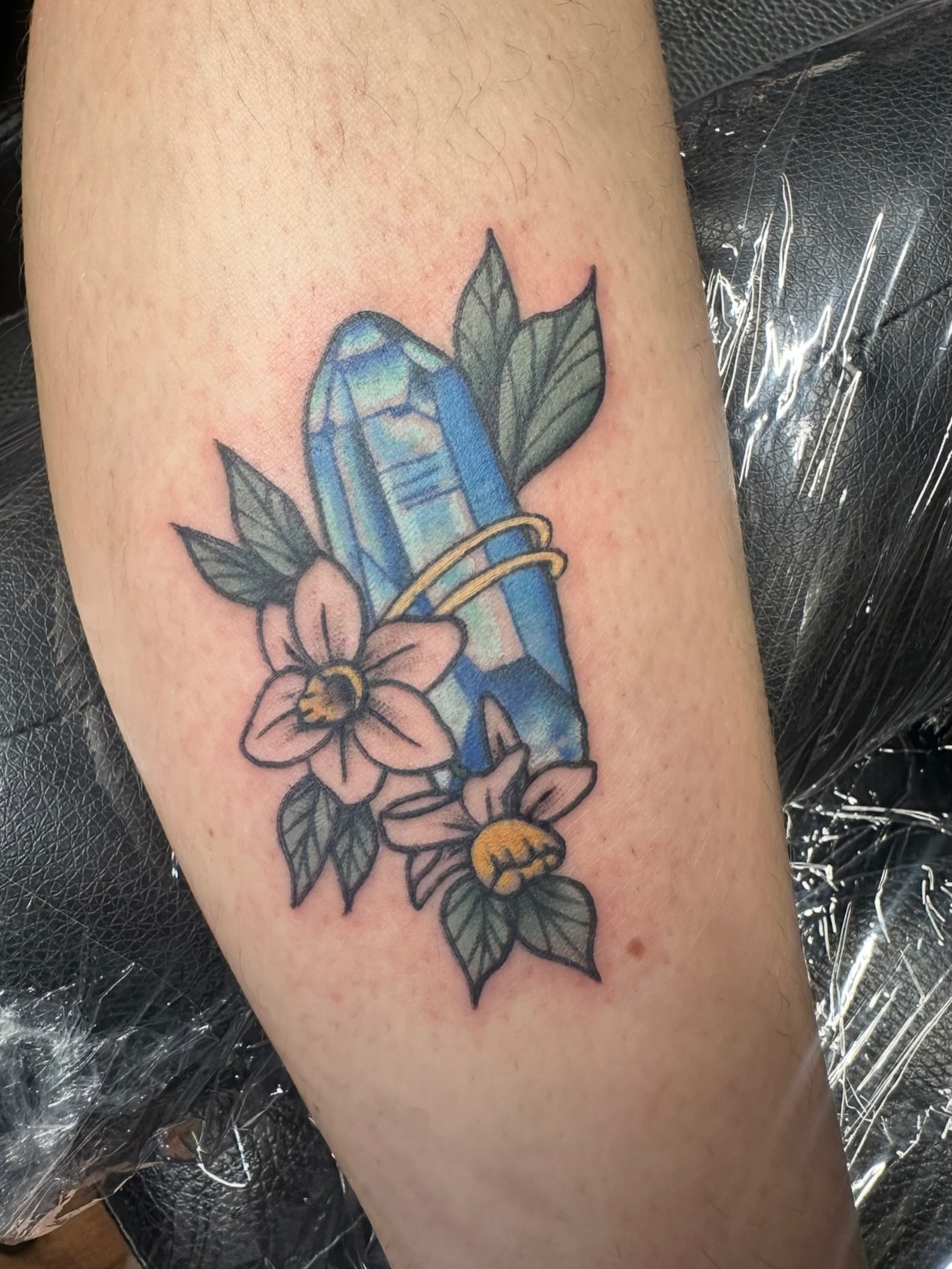 Quartz crystal and flowers realism tattoo on the forearm by Lindsey Bendsey