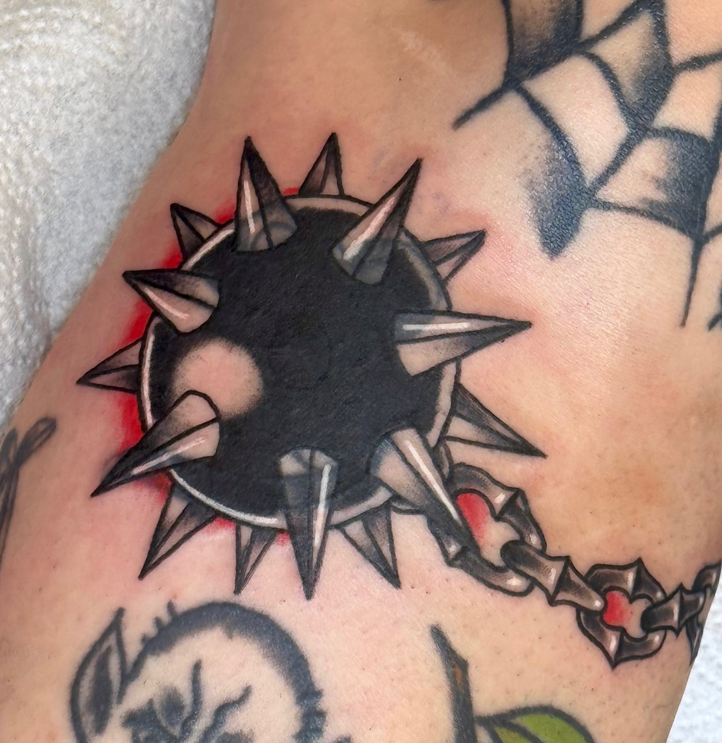 Spiked ball black and grey tattoo on the upper arm by Erica Mirella