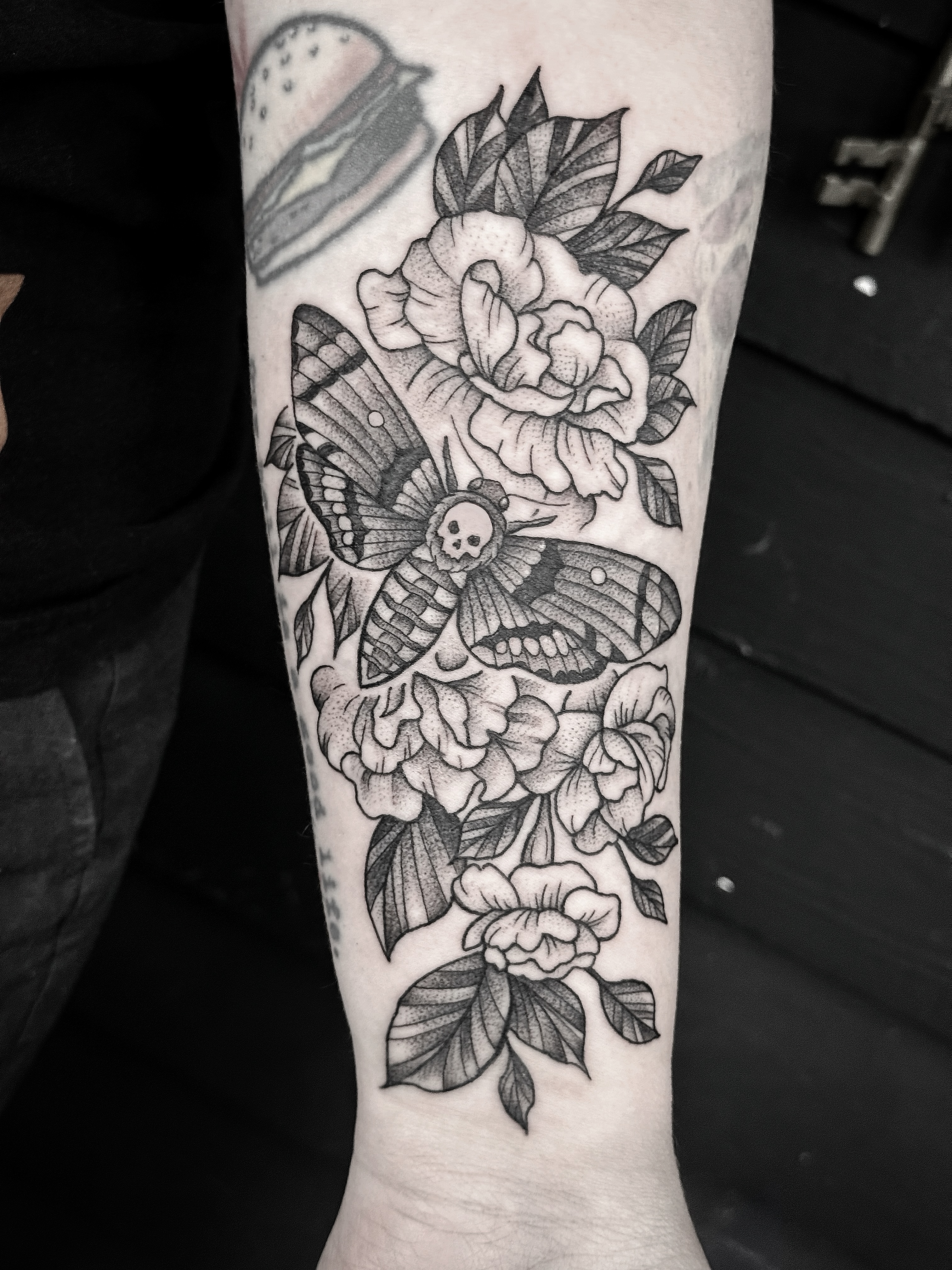 Moth and flowers American traditional tattoo on the forearm by Breezy Tucker