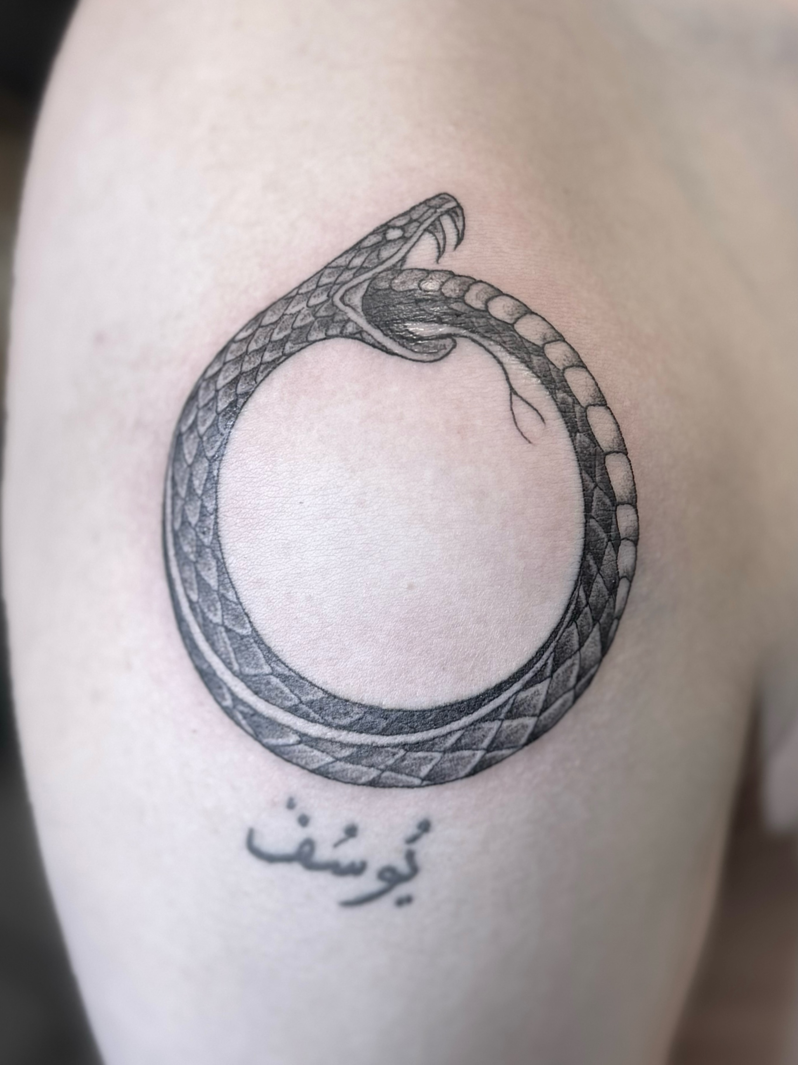 Snake black and grey tattoo on the upper arm by @luckybunnytat2