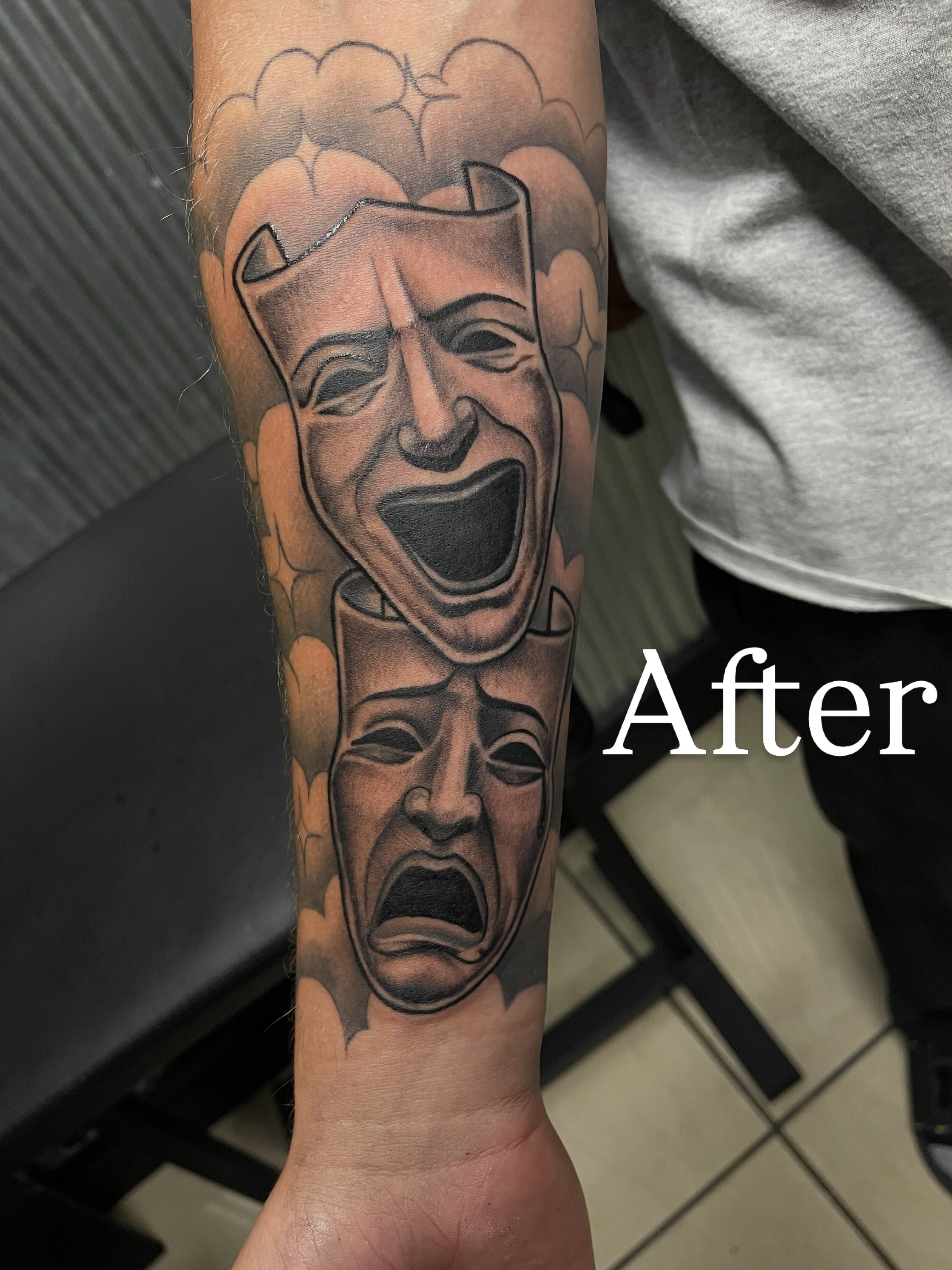 Theatrical masks black and grey tattoo on the forearm by Chris Torres