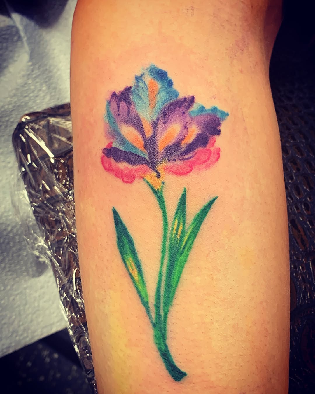 Iris watercolor tattoo on the forearm by El Kapitan