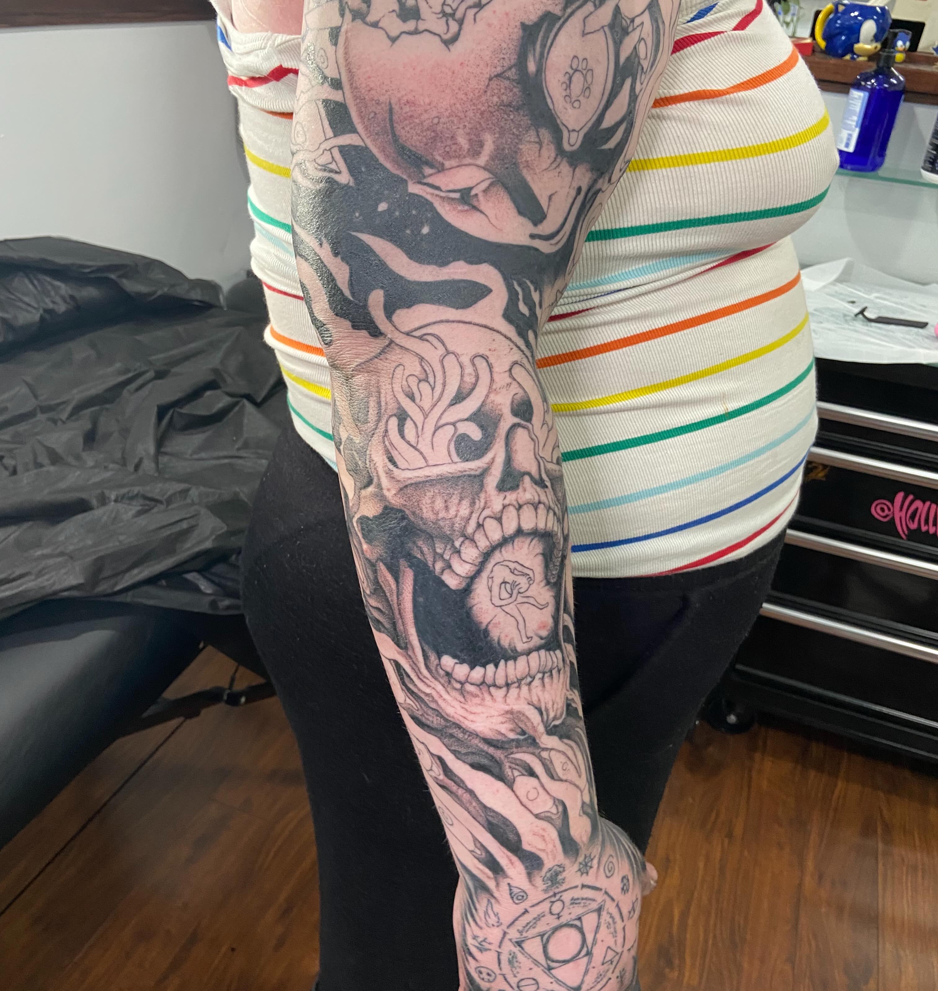 Skull and flames realism tattoo on the upper arm by Holly Redwinter