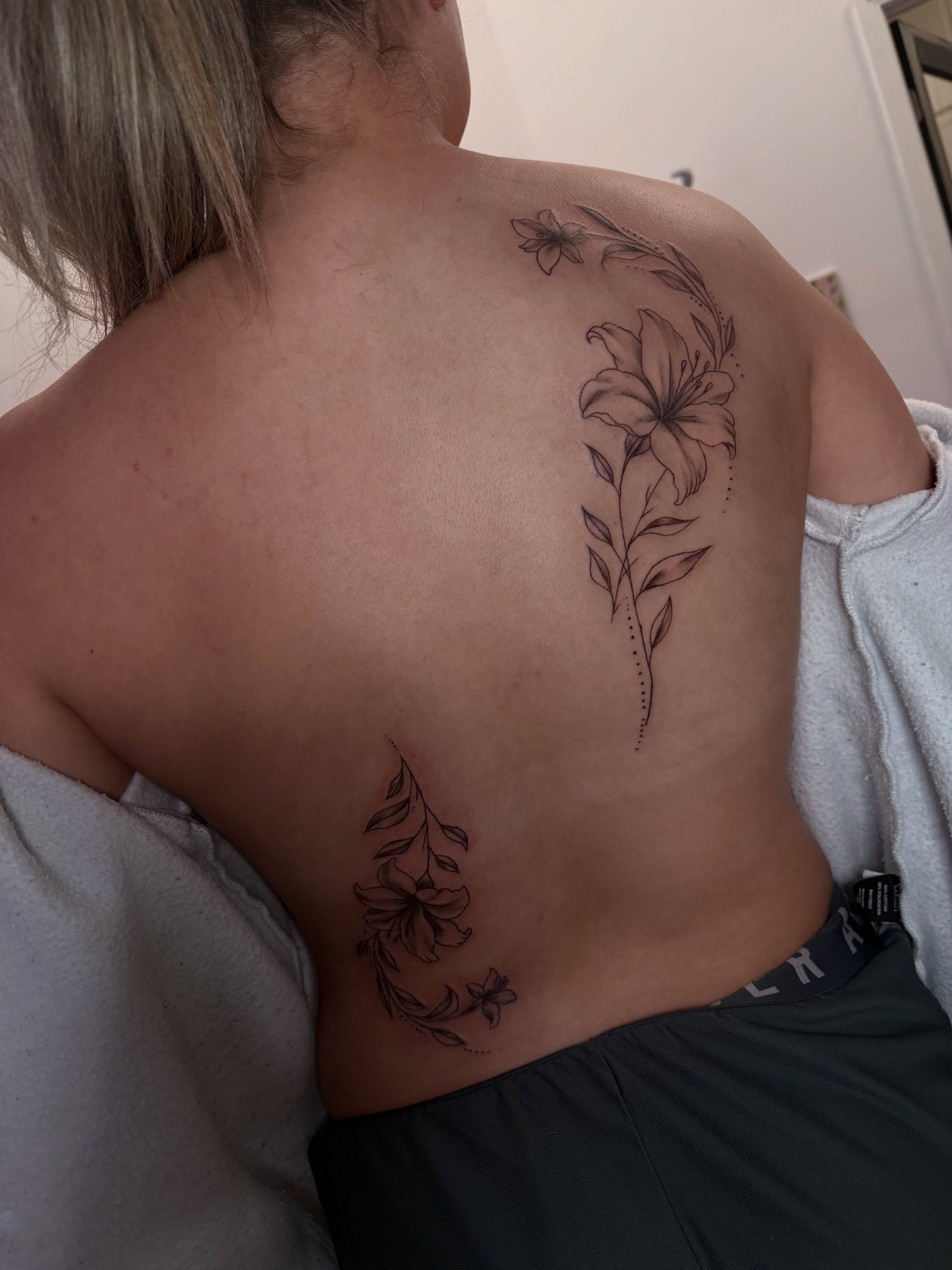 Lily and floral vine black and grey tattoo on the back by Cincinnati Tattoo Artist