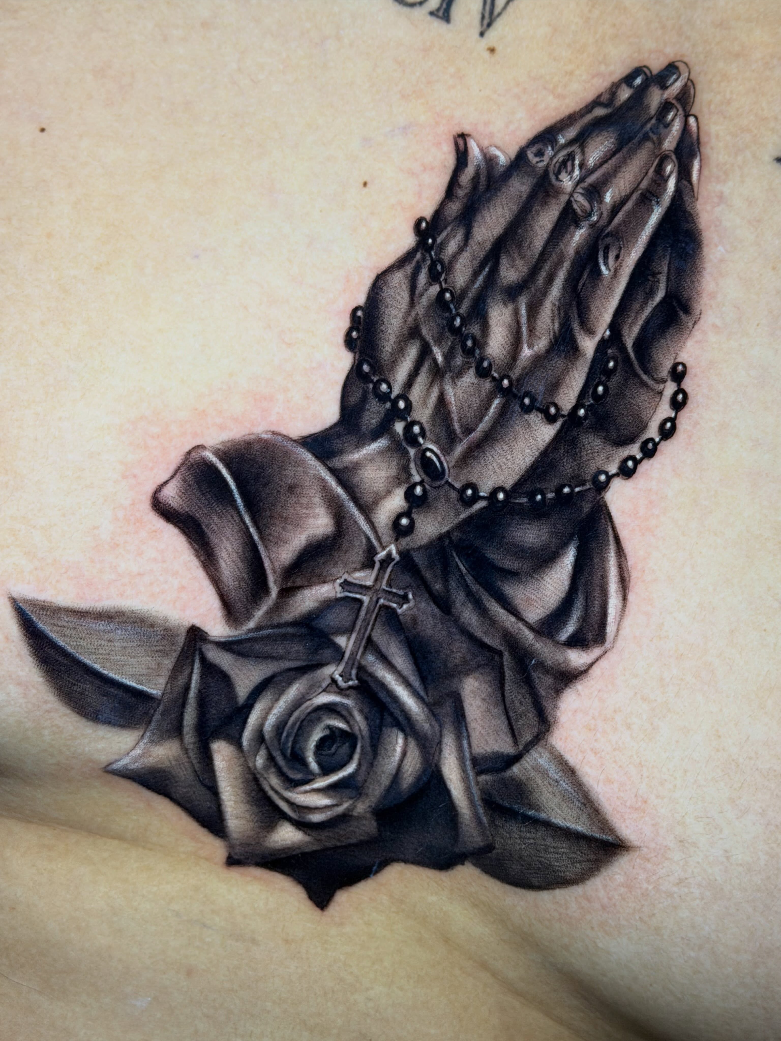 Praying hands with rosary and rose realism tattoo on the chest by Matthew Arguello