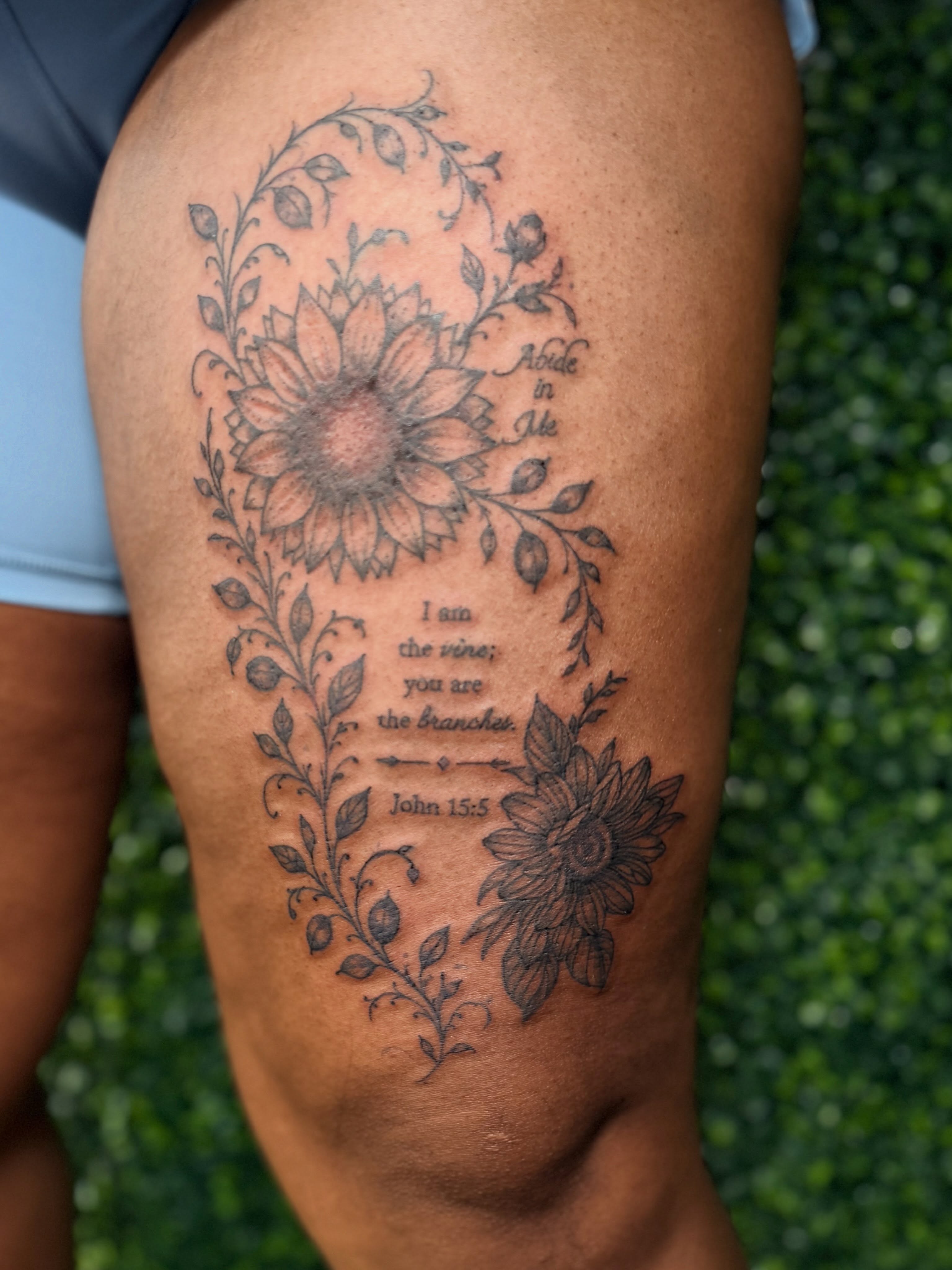 Sunflower and floral arrangement black and grey tattoo on the thigh by Alesia
